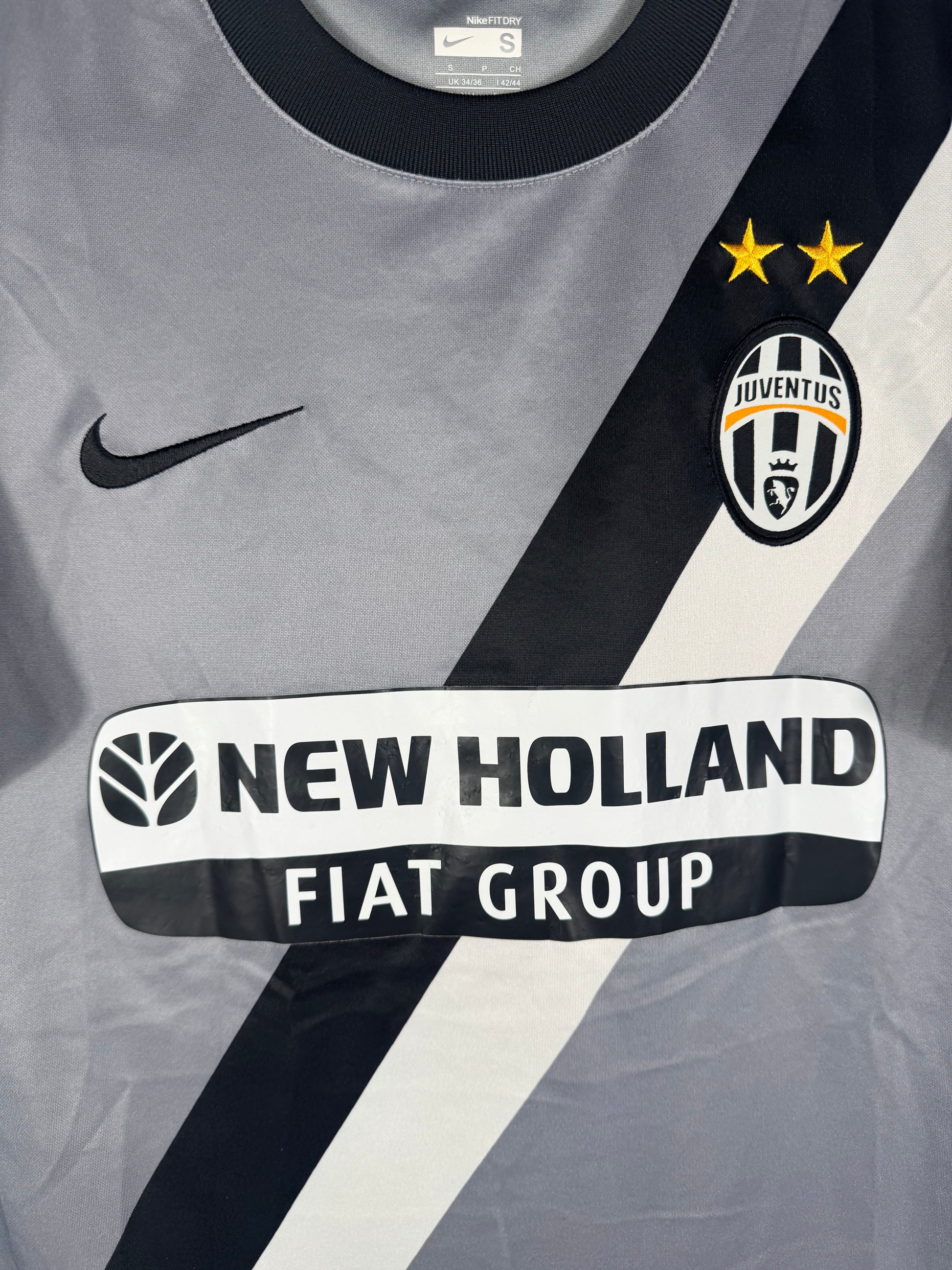 Gros plan sur l'écusson Juventus, le swoosh Nike et la bande diagonale noire et blanche.