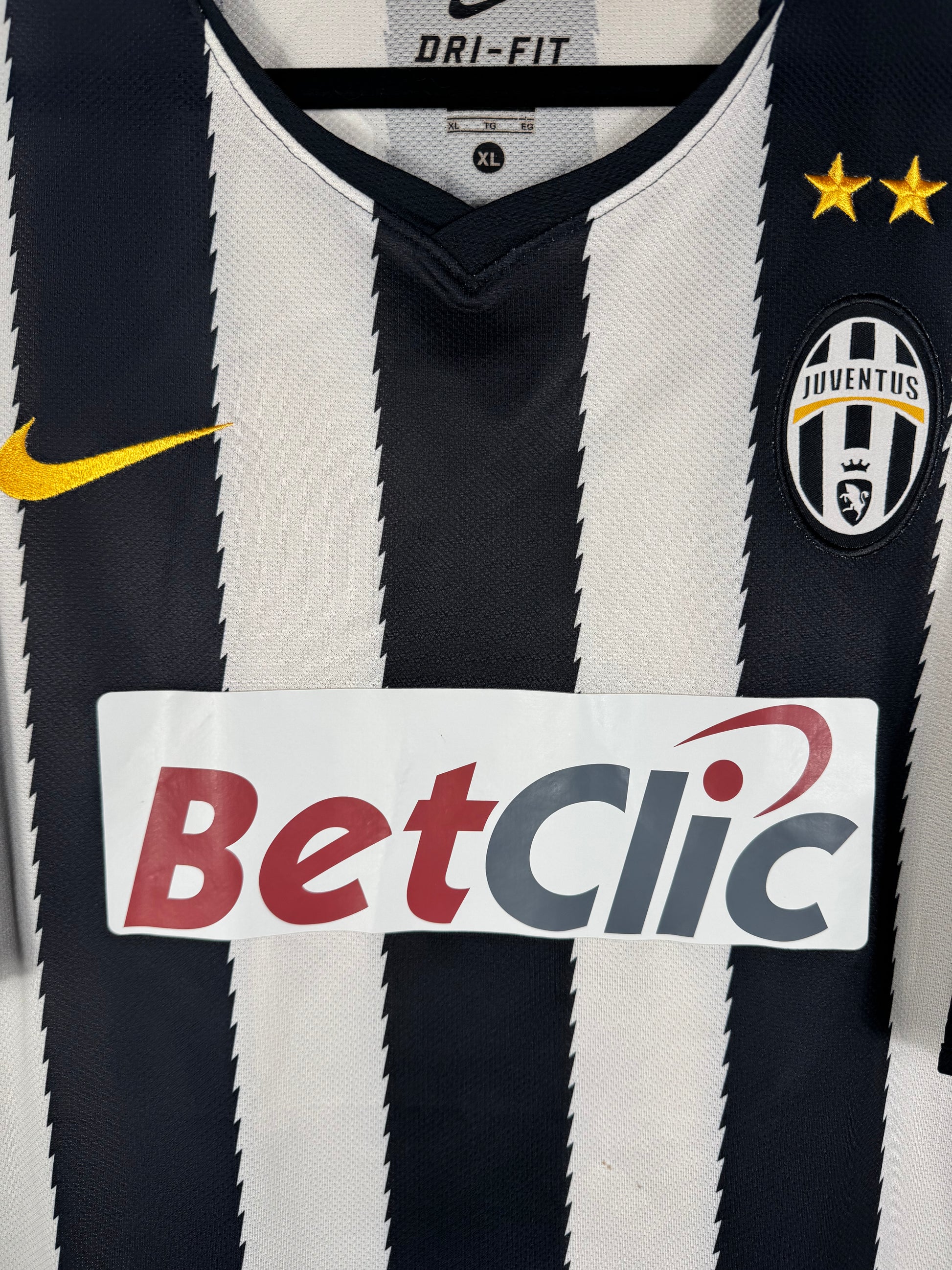Gros plan sur l'écusson de la Juventus et le logo Nike brodé sur les rayures dynamiques.