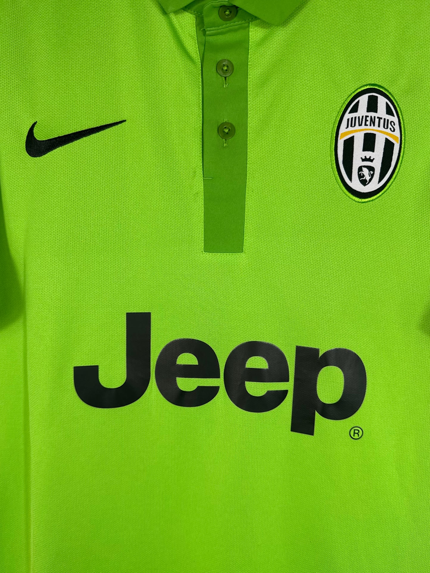 Gros plan sur l'écusson Juventus, le swoosh Nike et le sponsor Jeep sur fond vert.