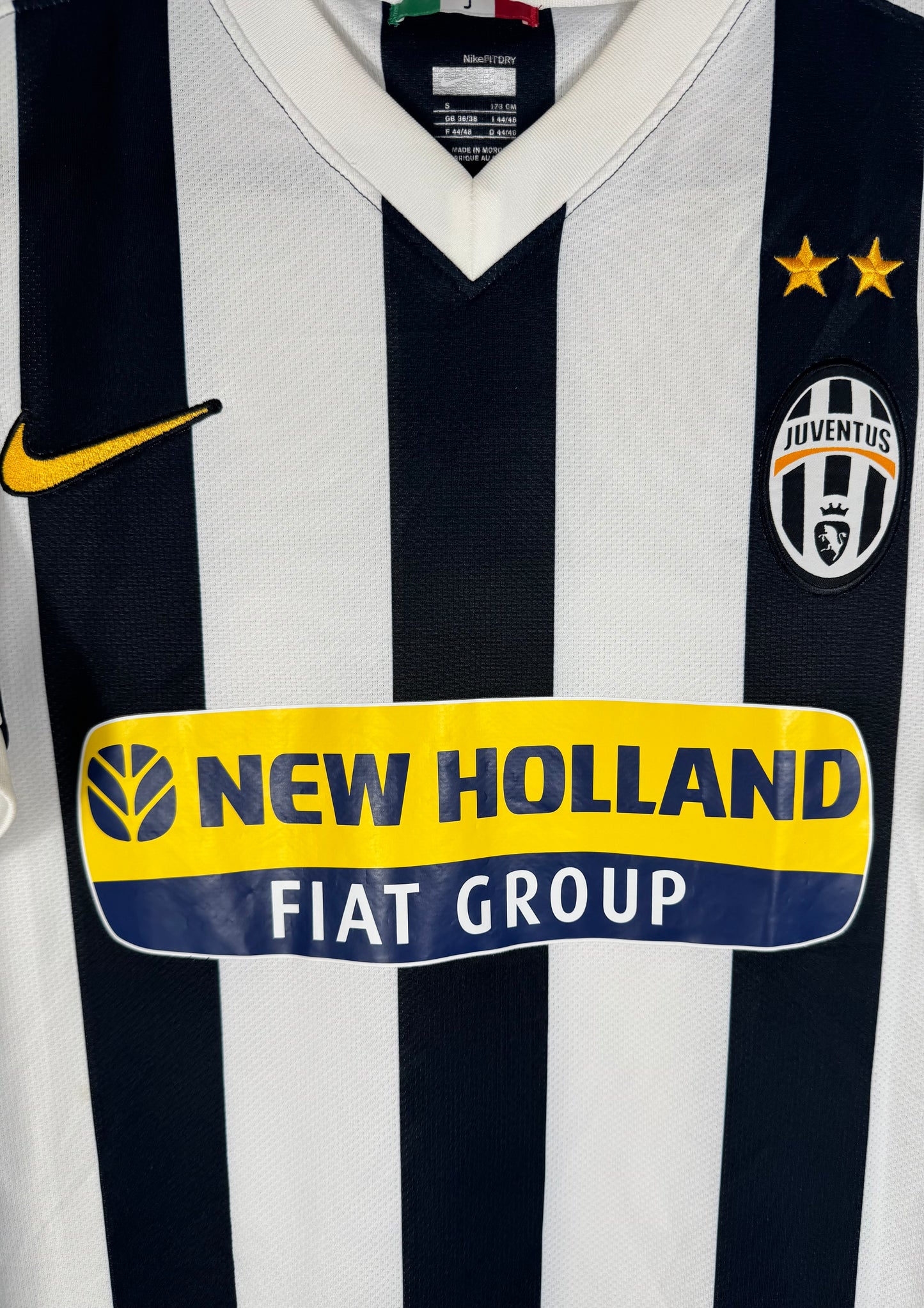 Gros plan sur l'écusson Juventus, le swoosh Nike jaune et le sponsor New Holland.