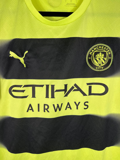 Gros plan sur l'écusson monochrome noir de Manchester City et le logo Puma sur le tissu jaune.