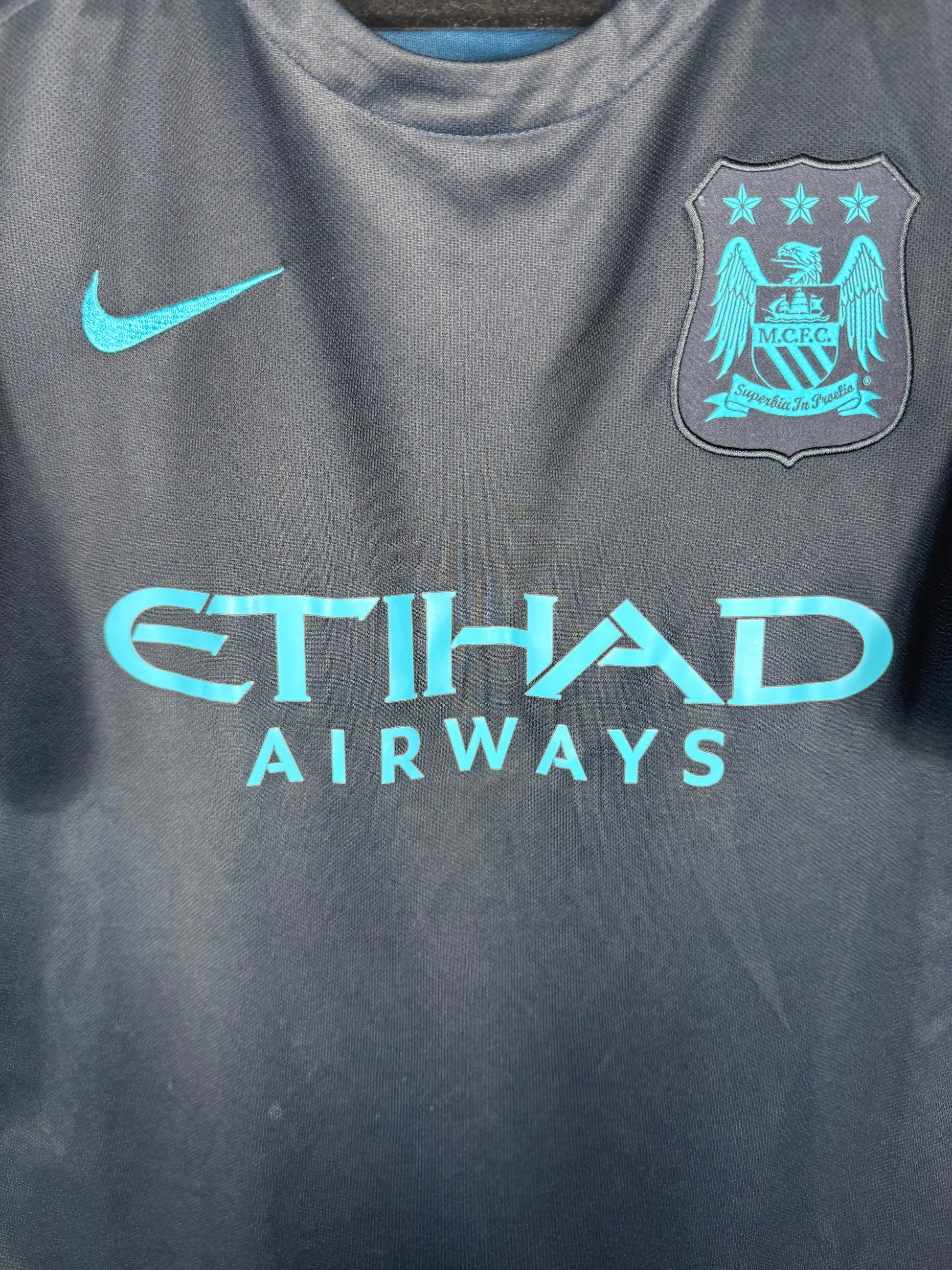 Gros plan sur l'écusson circulaire classique de Man City et le logo Nike bleu cie