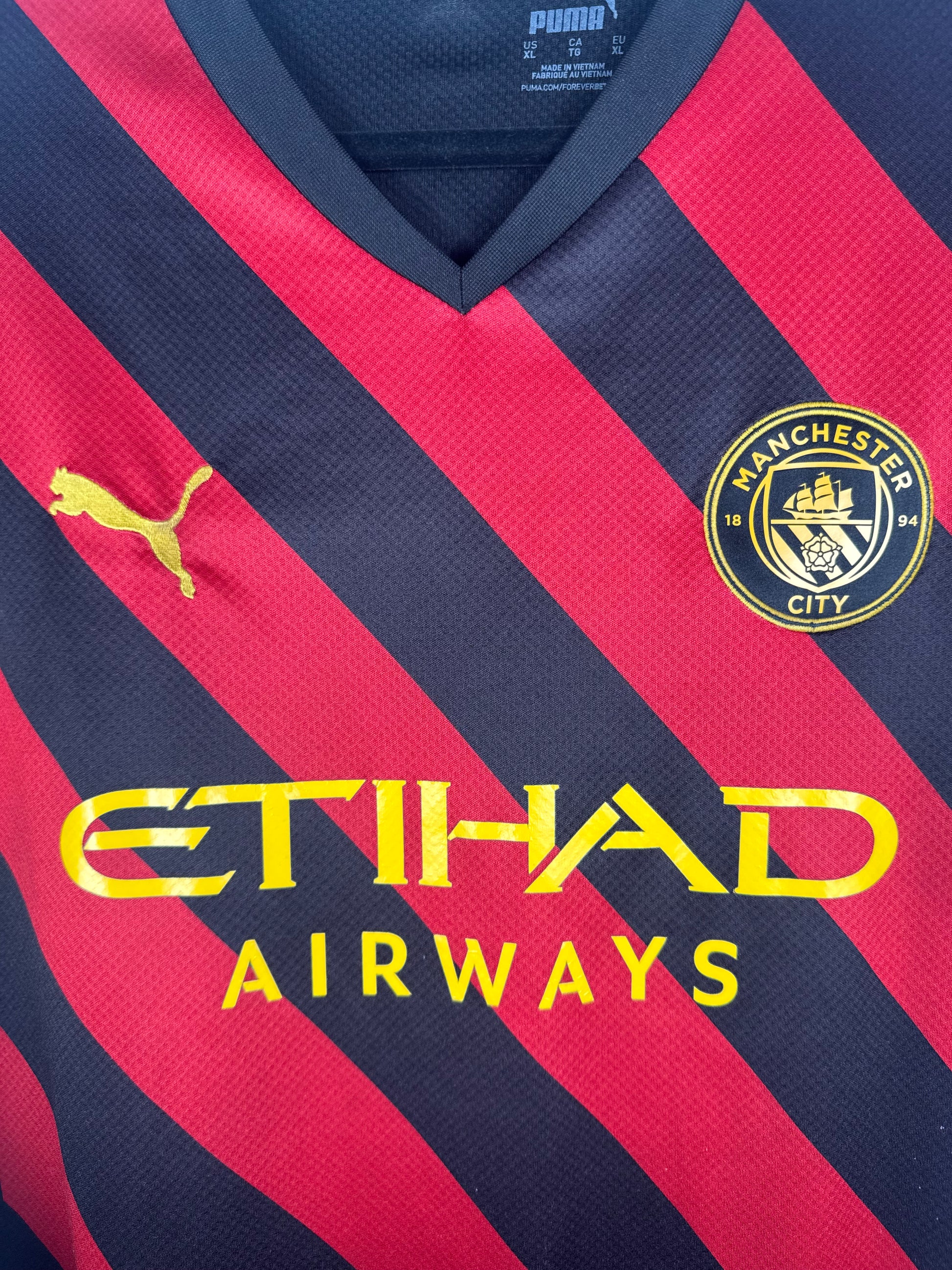 Gros plan sur l'écusson Manchester City et le sponsor Etihad Airways jaune.