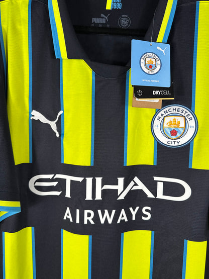 Gros plan sur l'écusson de Manchester City, le sponsor Etihad Airways et l'étiquette cartonnée Puma prouvant l'état neuf.