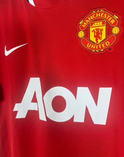 Gros plan sur l'écusson Manchester United, le swoosh Nike et le sponsor Aon.