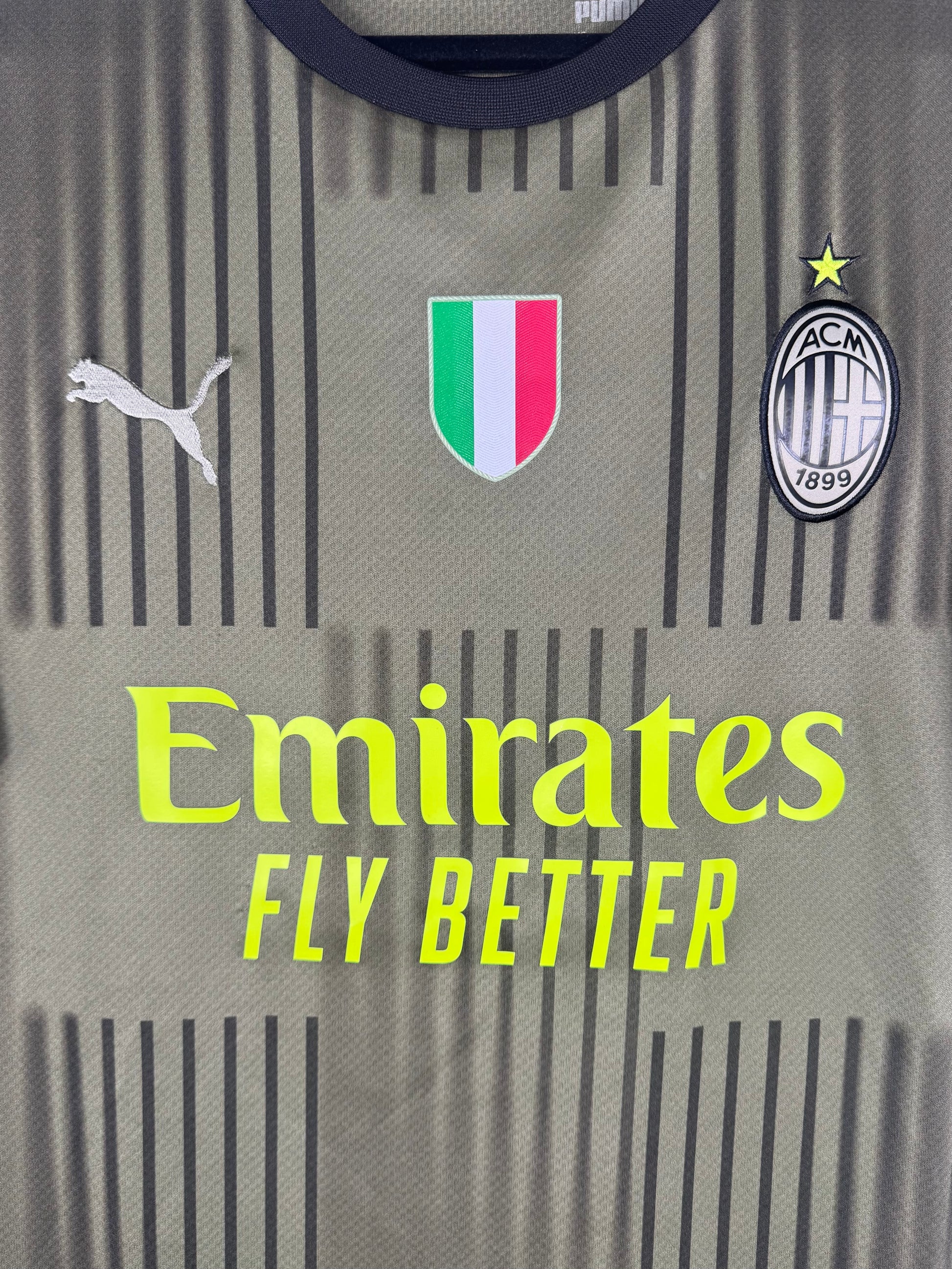 Gros plan sur le patch tricolore Scudetto, le logo Puma et l'écusson Milan monochrome.