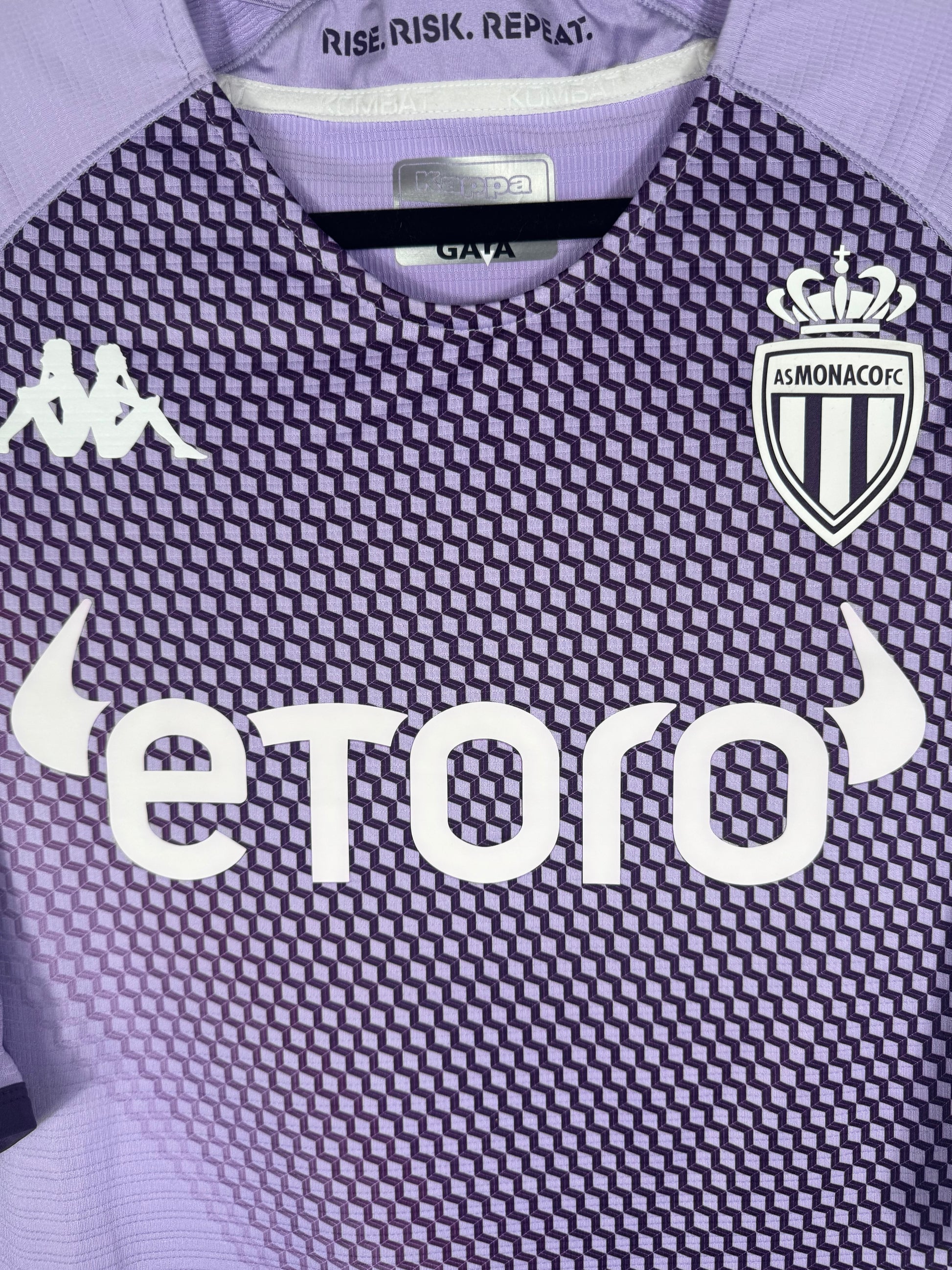 Gros plan sur la texture technique du tissu "Kombat Pro", l'écusson Monaco et sponsor eToro.