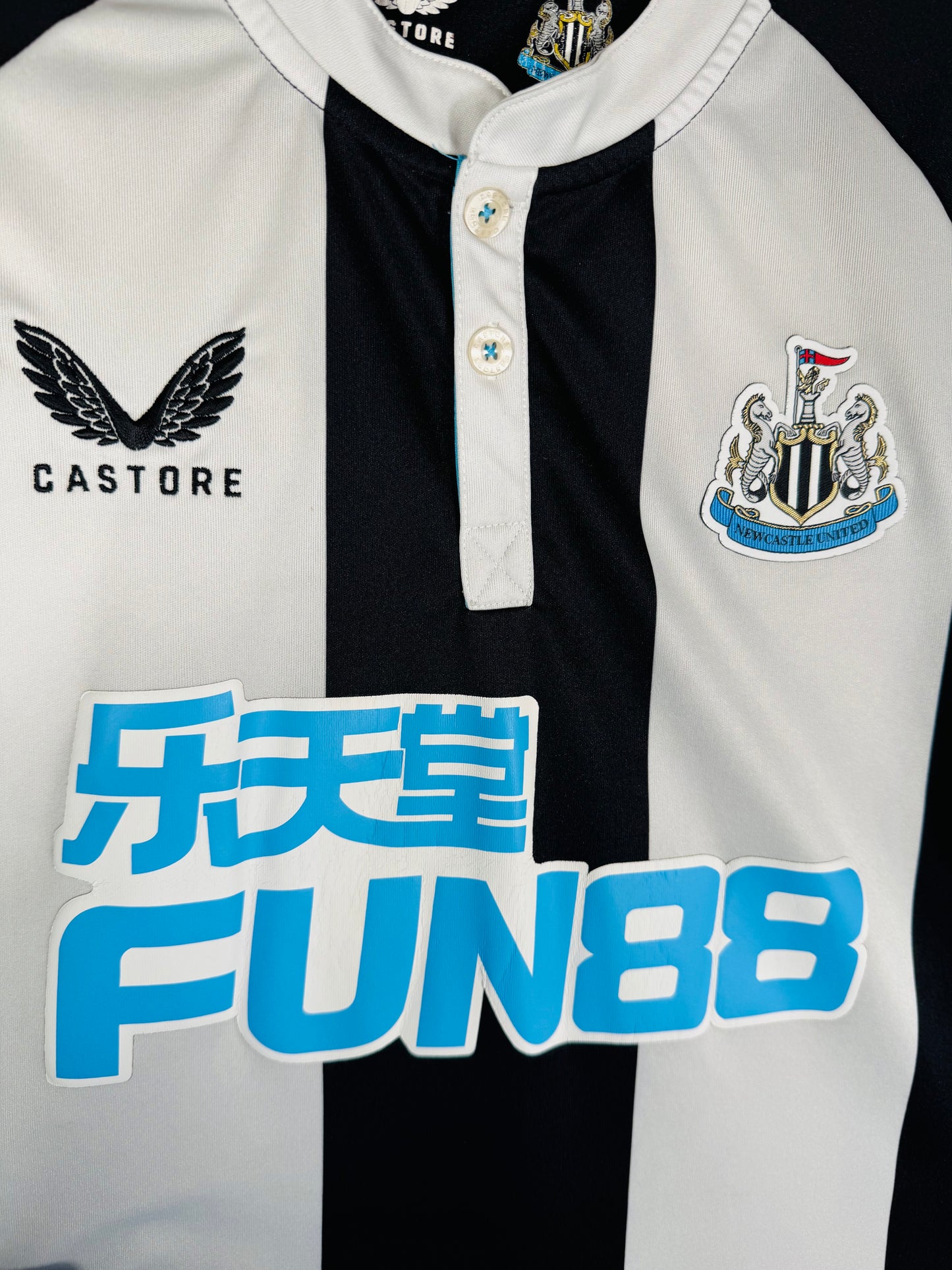 Gros plan sur l'écusson de Newcastle United brodé et le logo ailé de la marque Castore.