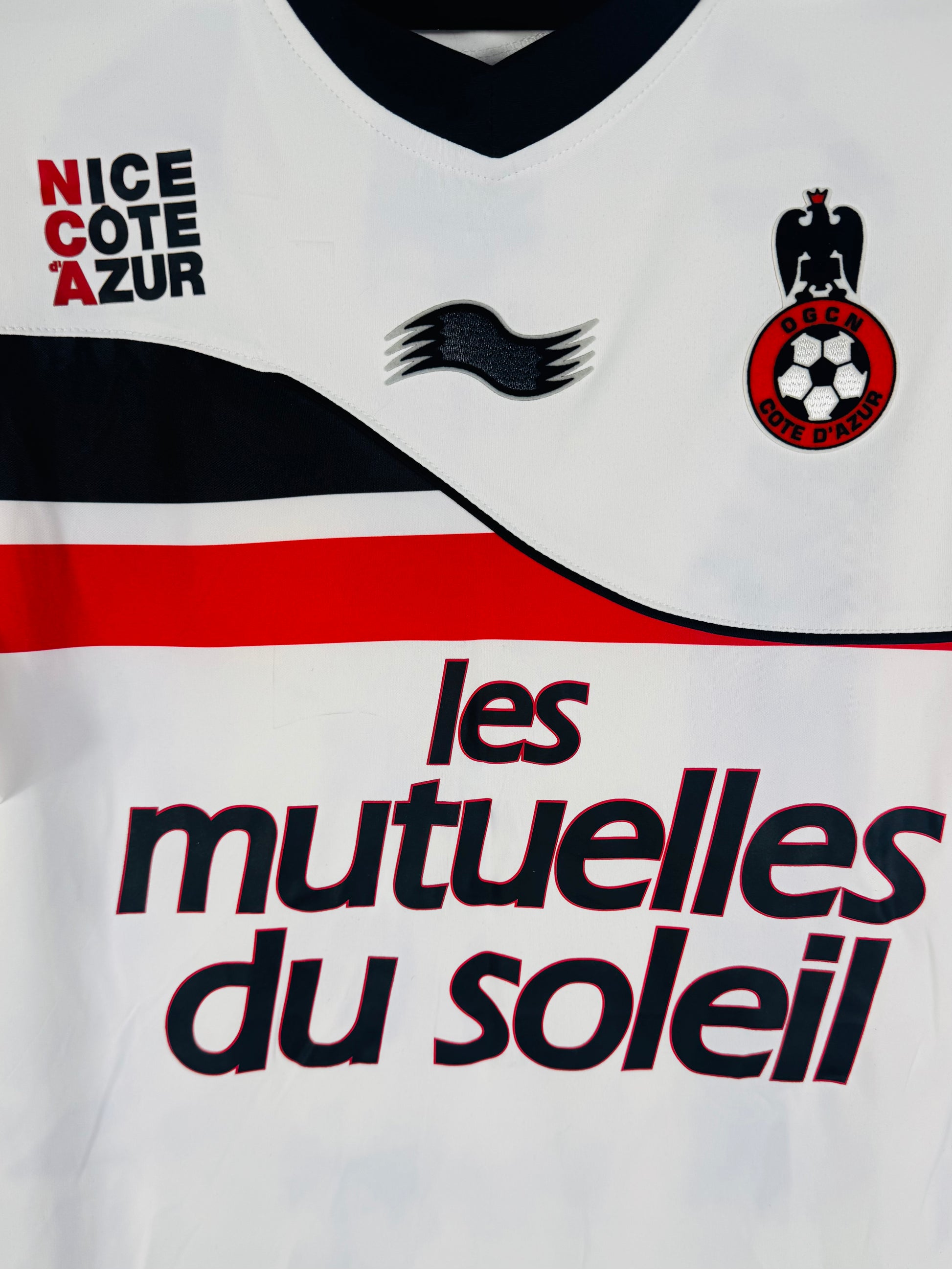 Gros plan sur l'écusson de l'OGC Nice et le design de la vague sur la poitrine.