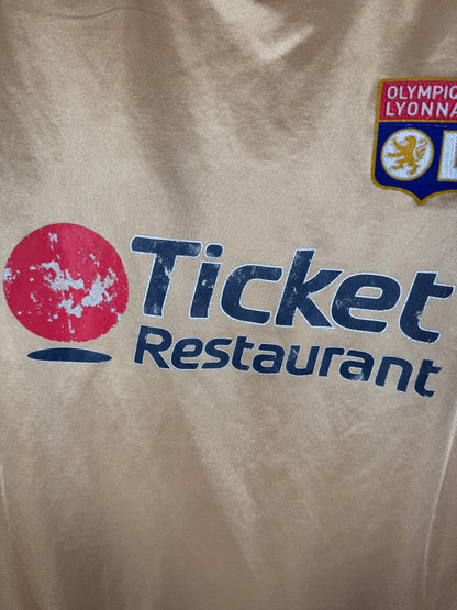 Gros plan sur l'écusson central de l'Olympique Lyonnais et le logo Umbro brodé.