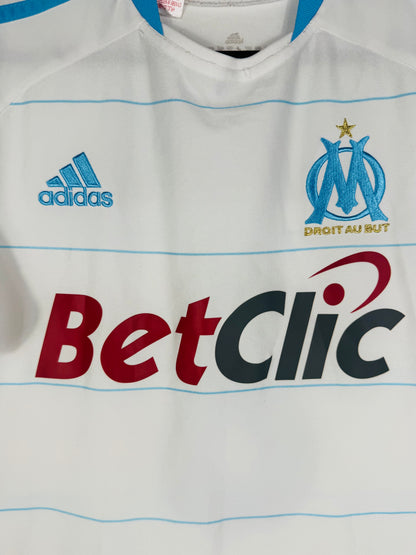 Gros plan sur l'écusson Olympique de Marseille, le logo Adidas bleu et le sponsor BetClic.