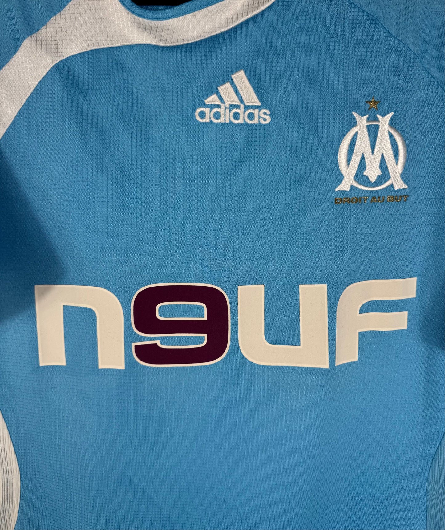 Gros plan sur l'écusson brodé de l'OM et le logo Adidas sur le template Teamgeist