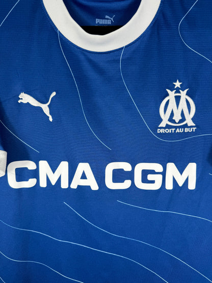 Gros plan sur l'écusson de l'Olympique de Marseille avec son étoile dorée et le logo Puma blanc.