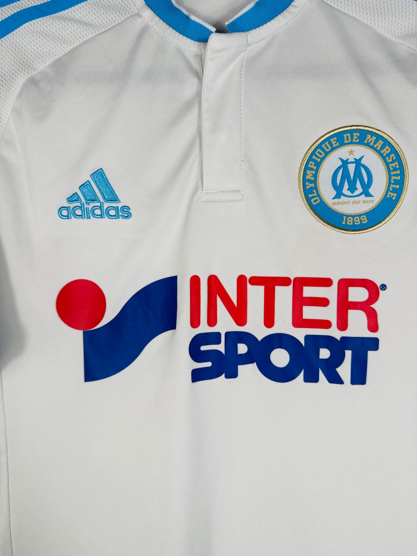 Gros plan sur l'écusson Olympique de Marseille et le logo Adidas brodés.