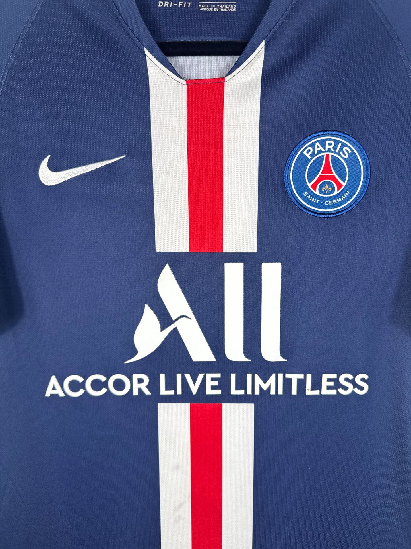 Gros plan sur l'écusson du Paris Saint-Germain et le swoosh Nike sur la bande rouge