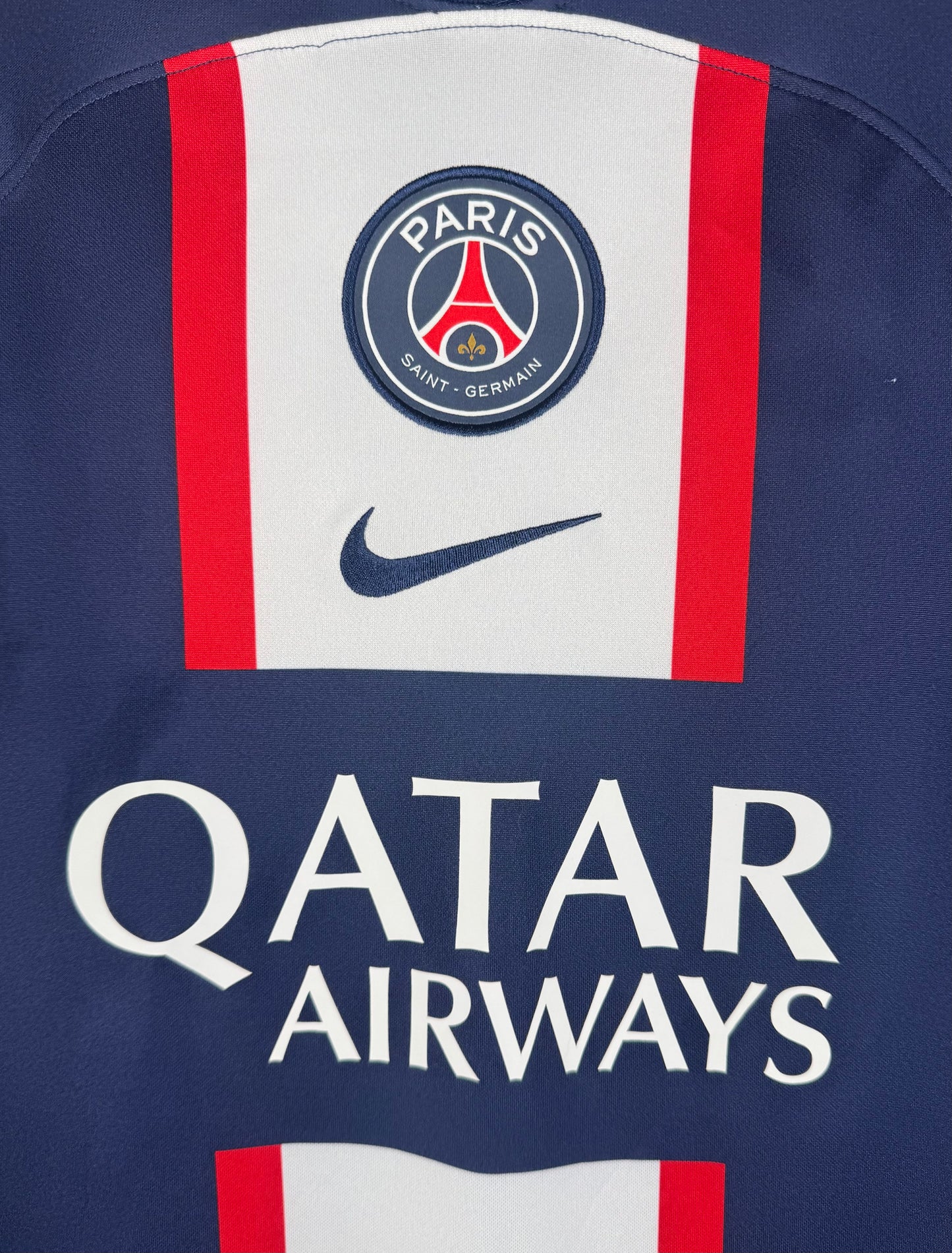Gros plan sur l'écusson Paris Saint-Germain et le sponsor Qatar Airways sur la bande centrale.