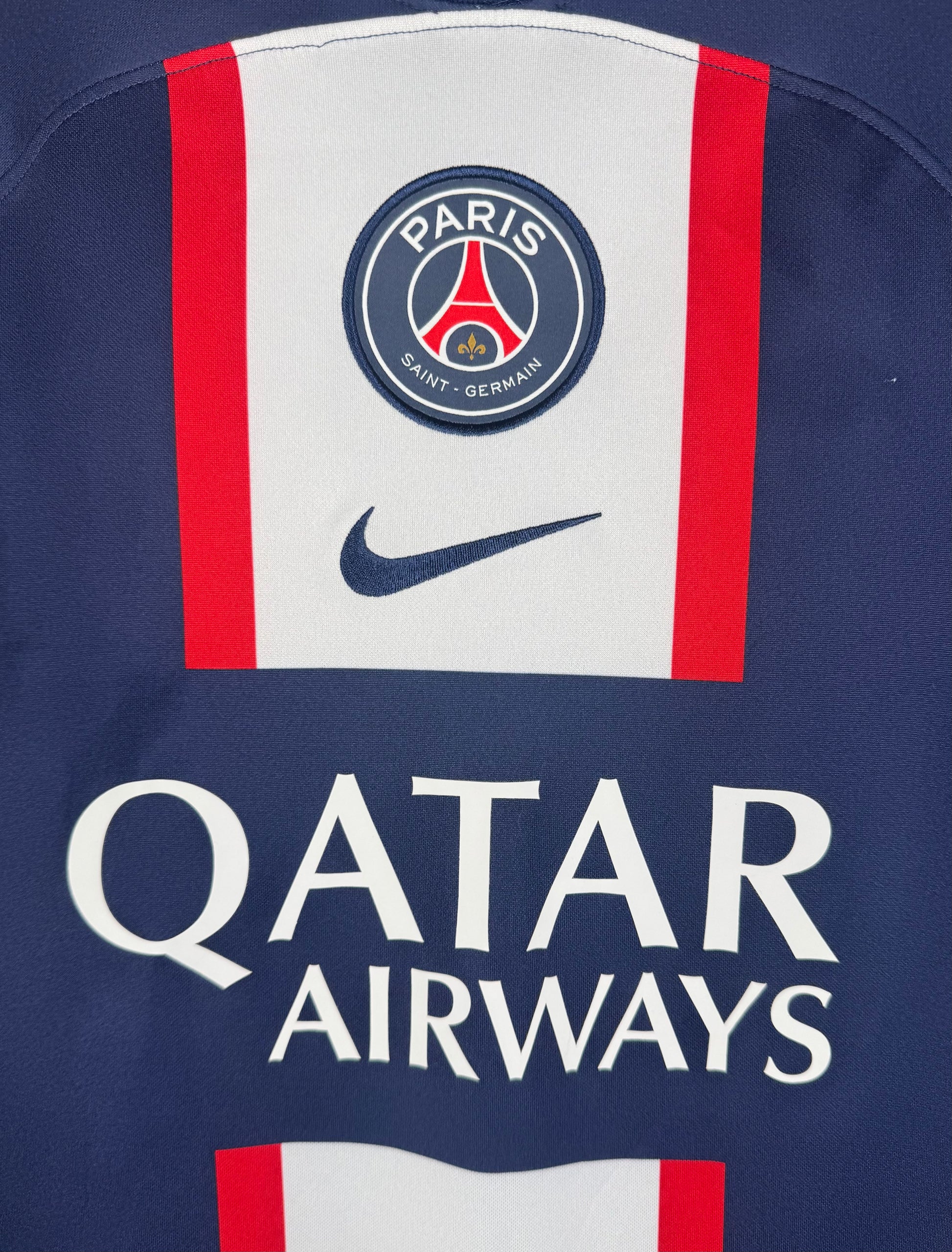 Gros plan sur l'écusson Paris Saint-Germain et le sponsor Qatar Airways sur la bande centrale.