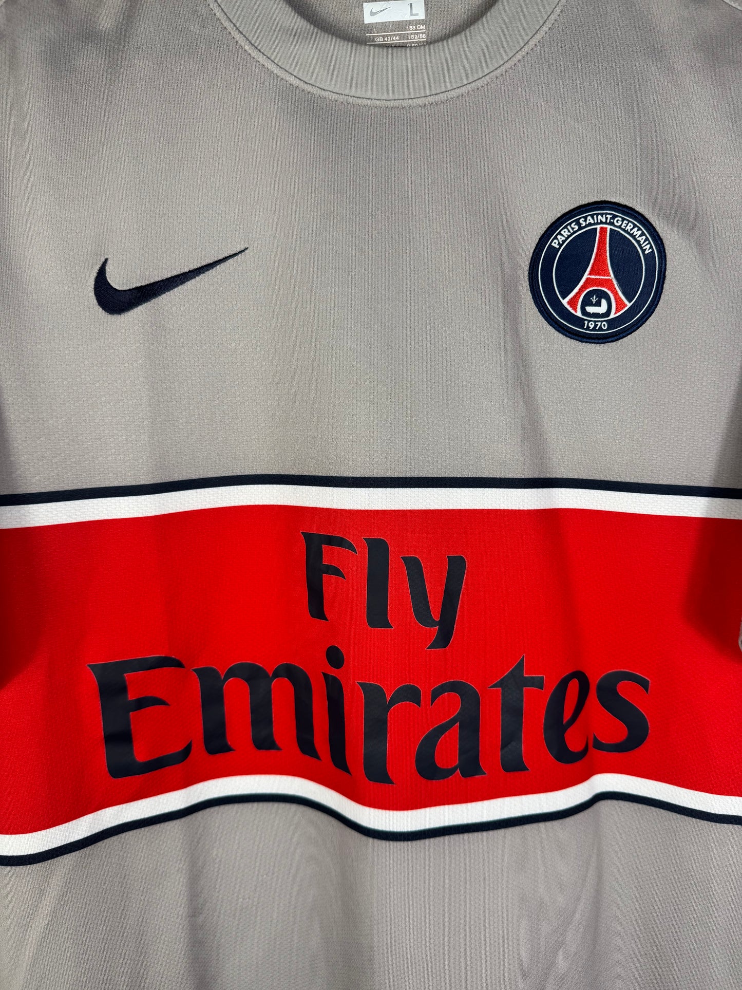 Gros plan sur l'écusson du Paris Saint-Germain et le logo Nike au-dessus de la bande rouge.
