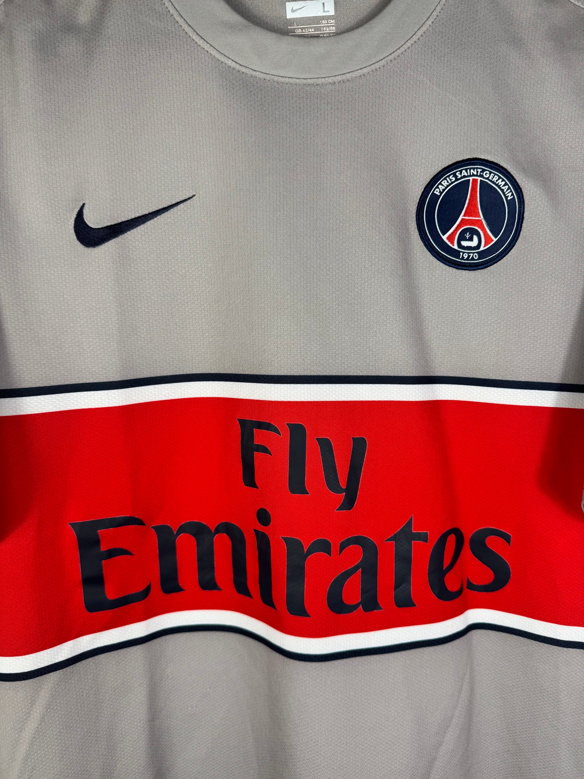 Gros plan sur l'écusson du Paris Saint-Germain et le logo Nike au-dessus de la bande rouge.