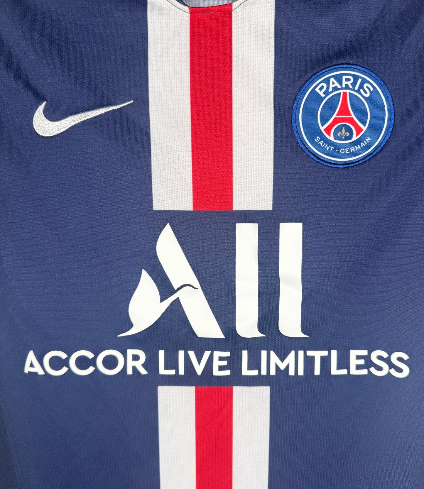 Gros plan sur l'écusson Paris Saint-Germain et le logo Nike sur la bande Hechter tissée.
