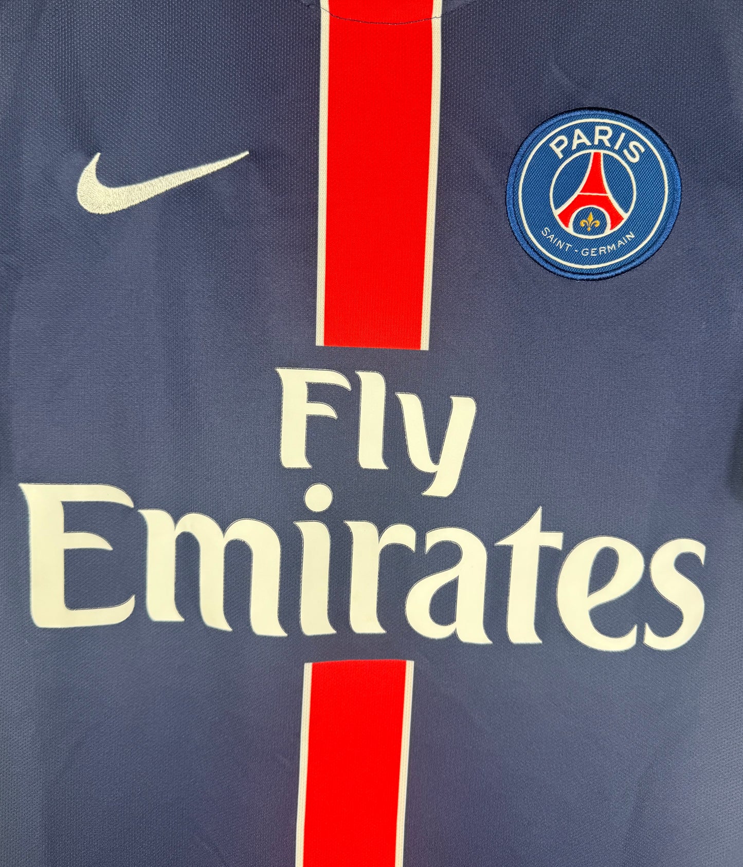 Gros plan sur l'écusson Paris Saint-Germain et le logo Nike sur la bande rouge.