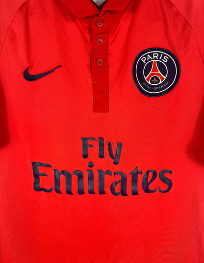 Gros plan sur l'écusson Paris Saint-Germain et le sponsor Fly Emirates sur fond rouge.