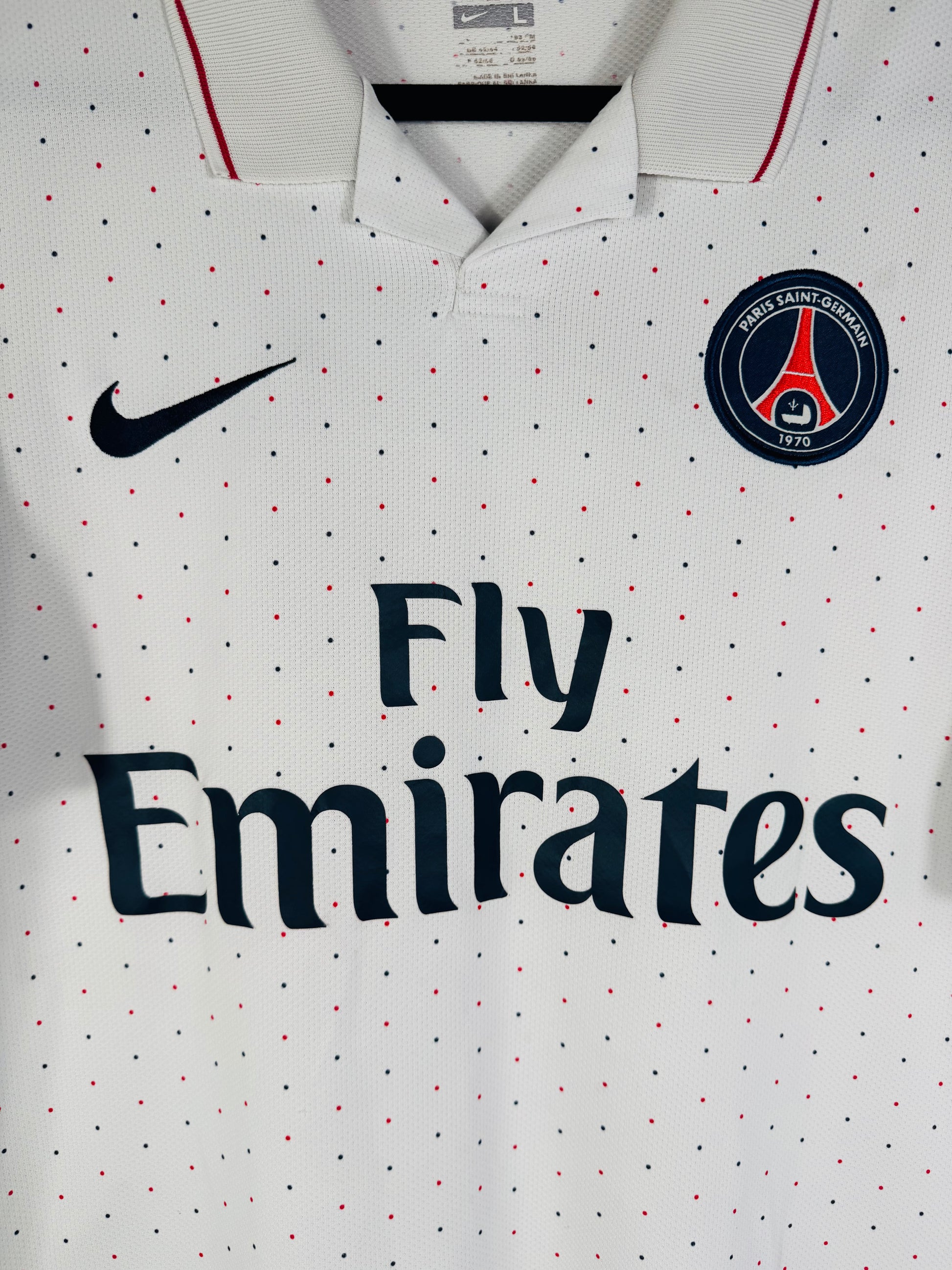Gros plan sur l'écusson du Paris Saint-Germain et le logo Nike noir brodés sur le tissu à pois.