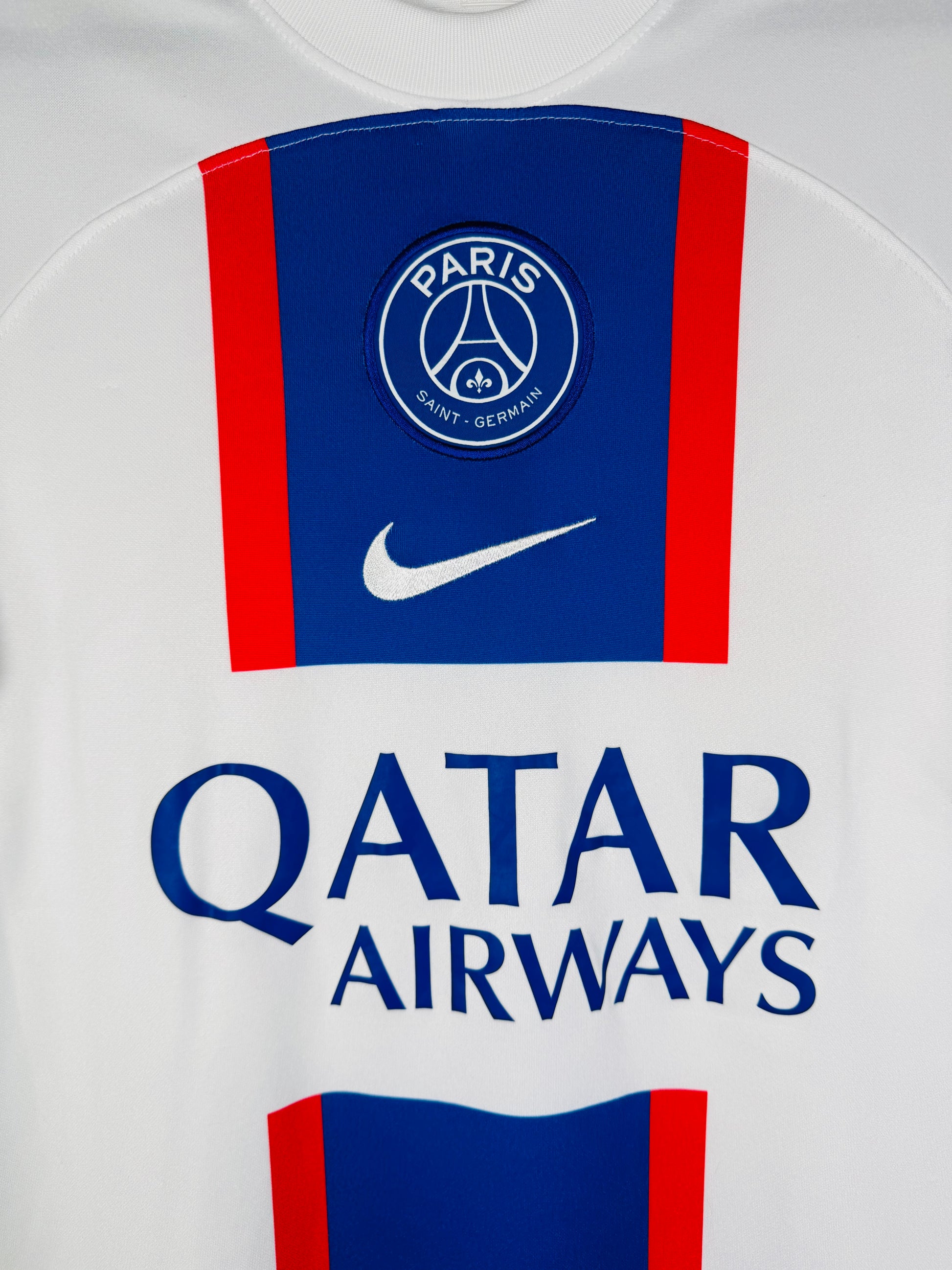 Gros plan sur l'écusson du Paris Saint-Germain et le logo Nike brodés sur la bande centrale.