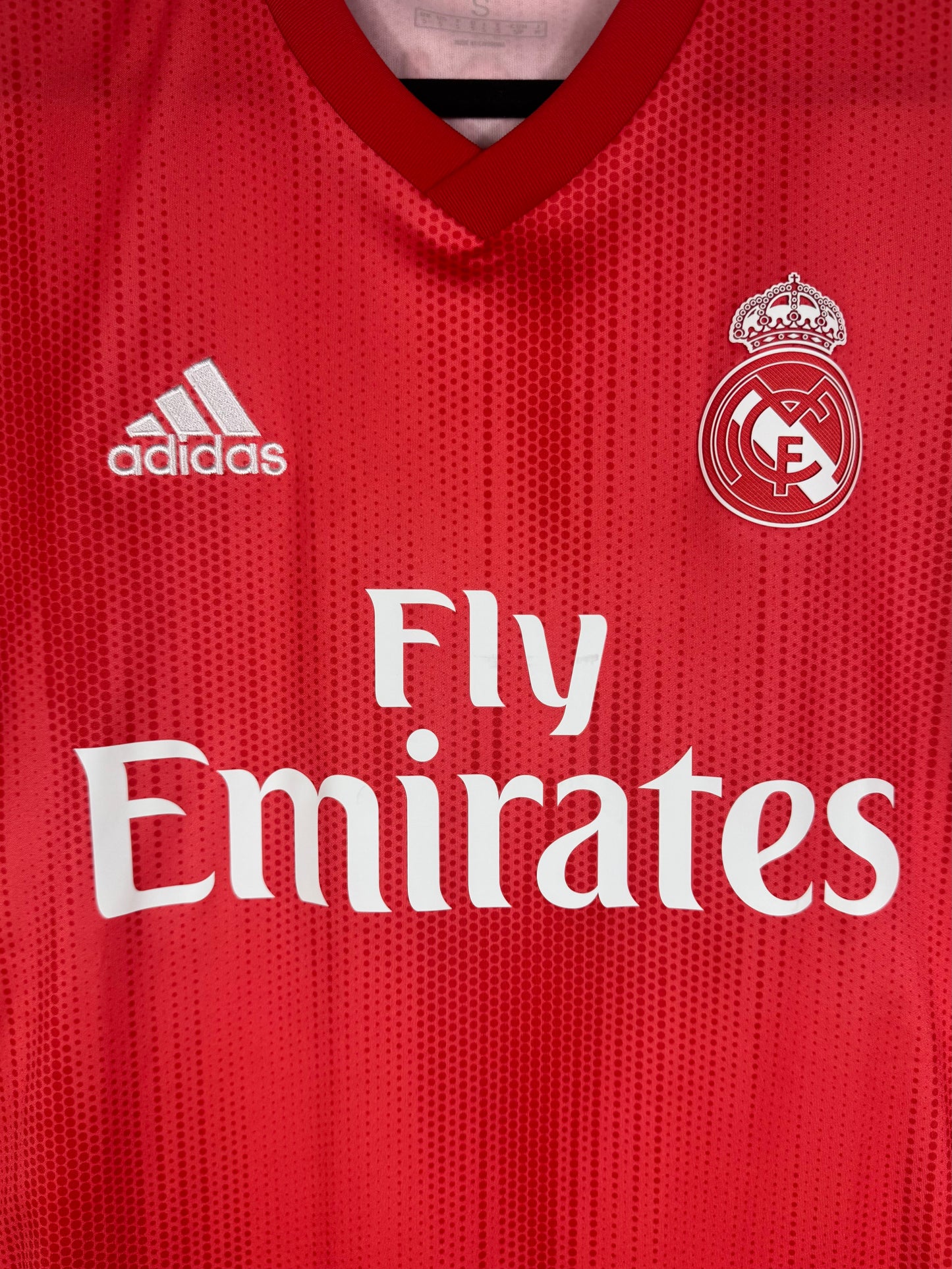 Gros plan sur l'écusson thermocollé du Real Madrid et le sponsor Fly Emirates blanc.