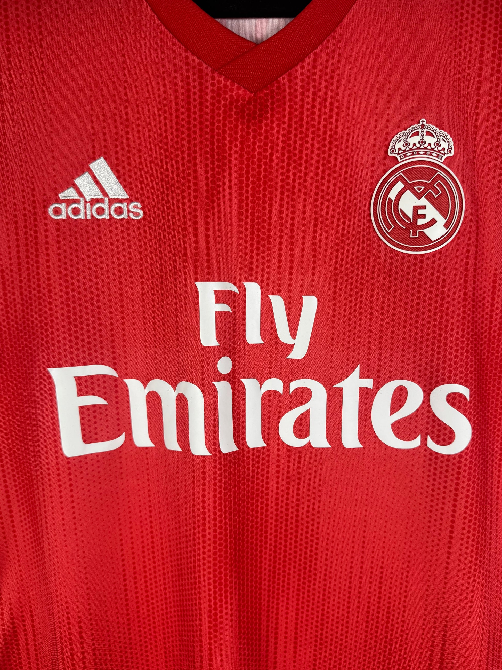 Gros plan sur l'écusson Real Madrid et le sponsor Fly Emirates sur le tissu recyclé Parley.