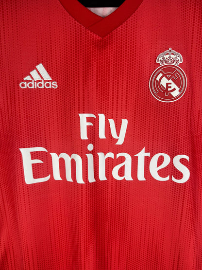 Gros plan sur l'écusson Real Madrid et le sponsor Fly Emirates sur le tissu recyclé Parley.
