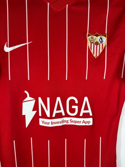 Gros plan sur l'écusson du Sevilla FC et le logo Nike blancs thermocollés sur le tissu rouge "Pro Version".