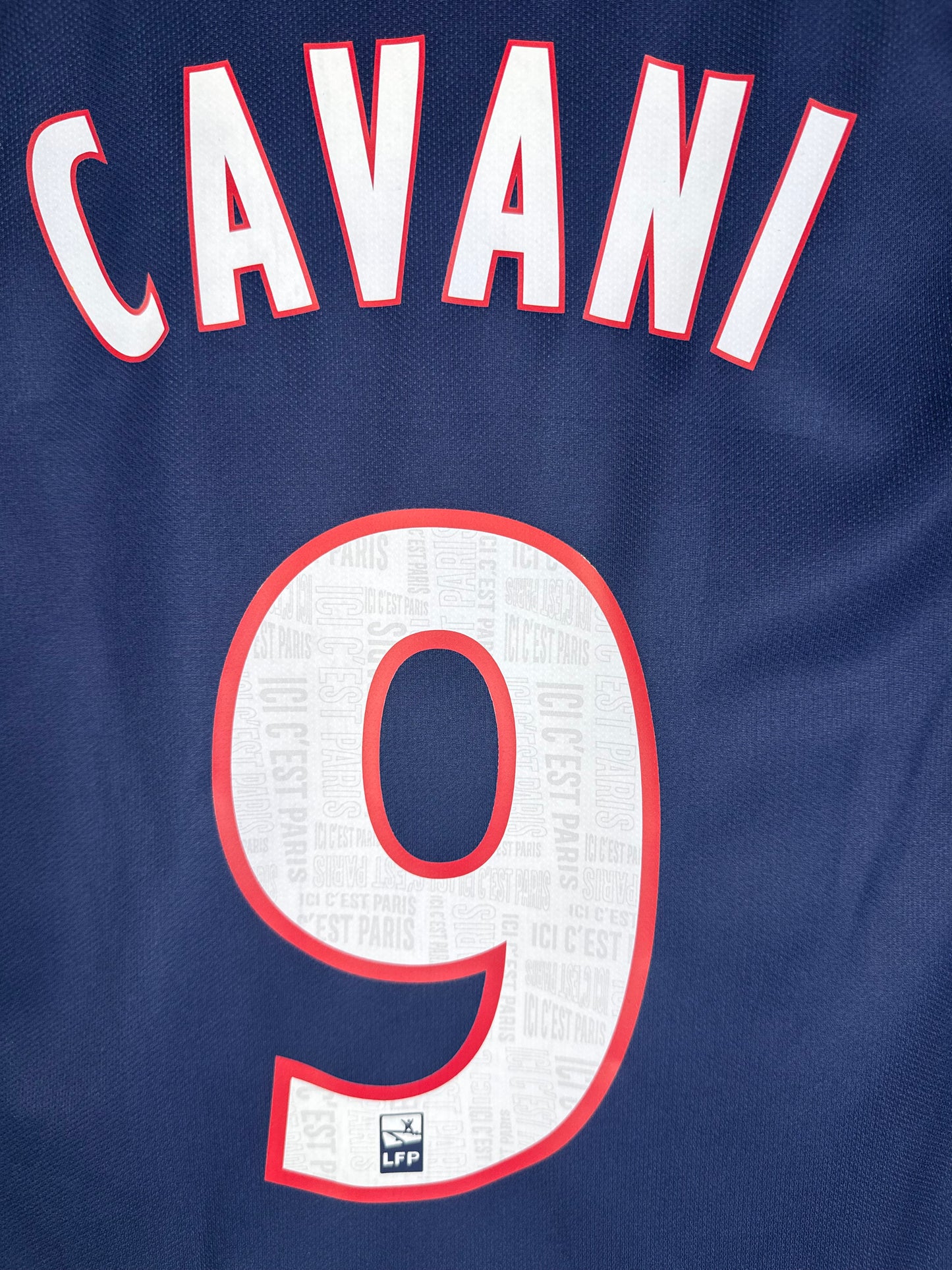 Zoom sur le nom CAVANI et le numéro 9 blanc avec contour rouge.