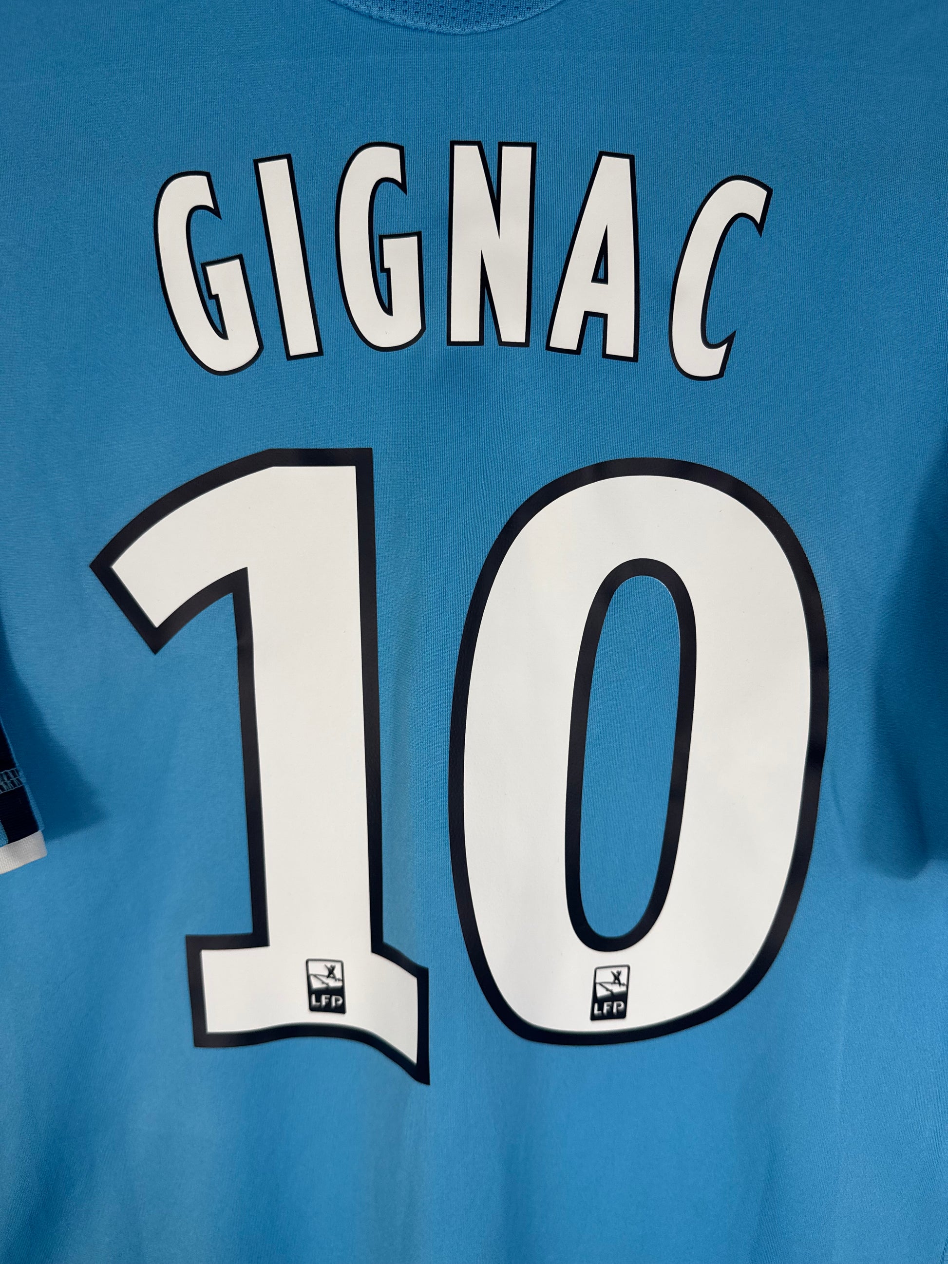 Zoom sur le nom GIGNAC et le numéro 10 blanc avec contour noir.