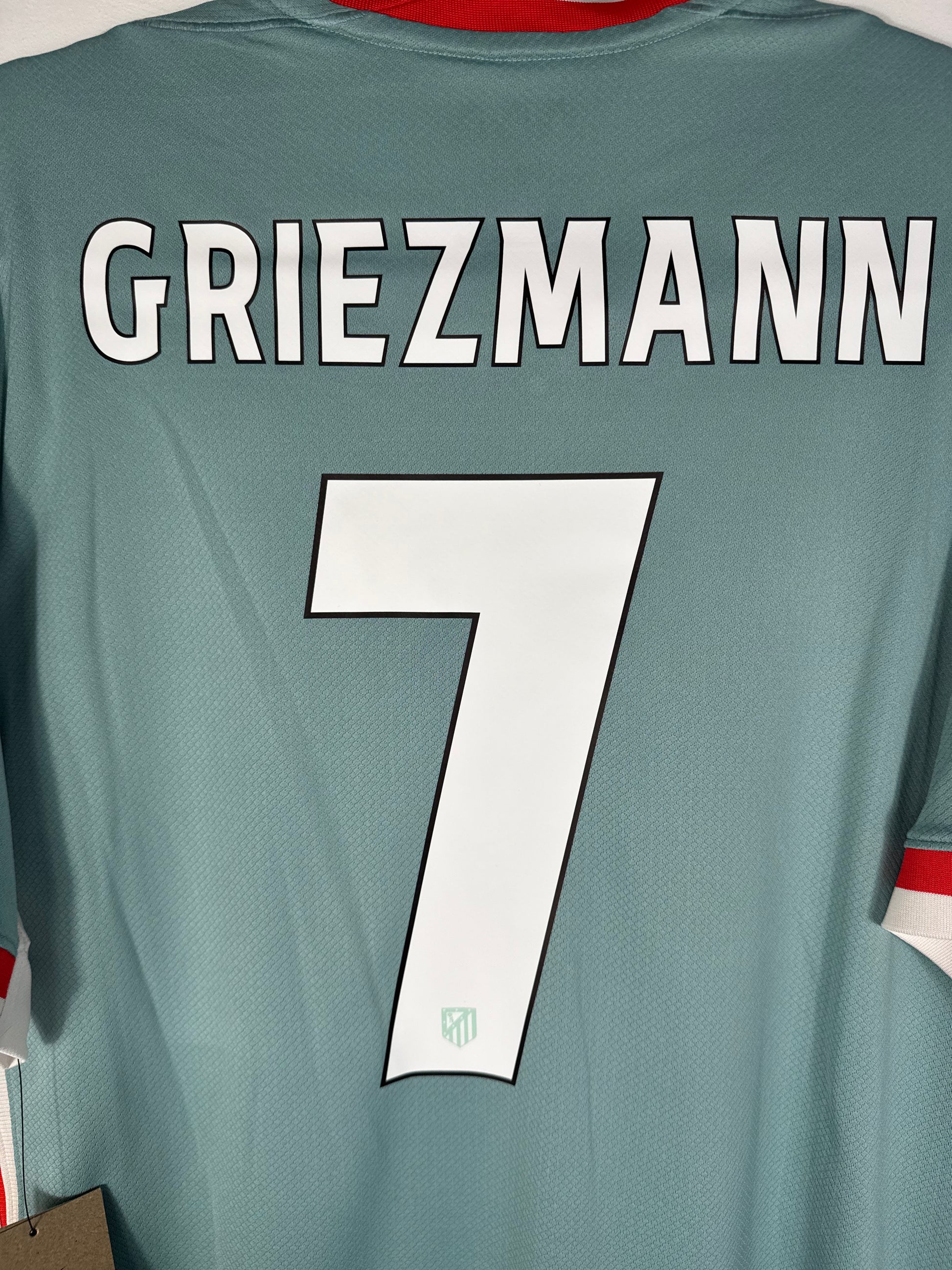 Zoom sur le nom GRIEZMANN et le numéro 7 rouge, police officielle de l'Atletico Madrid 2025.