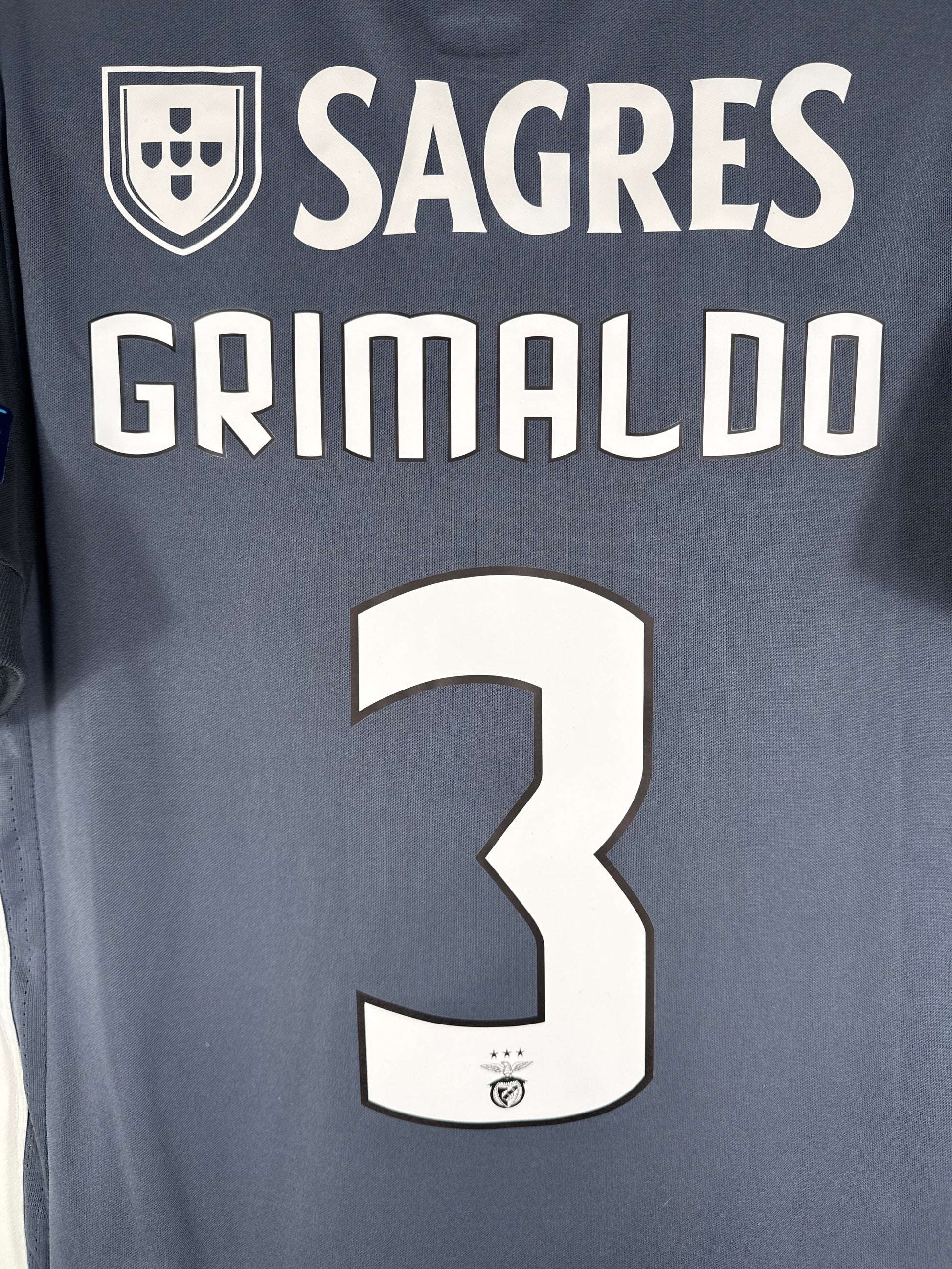 Zoom sur le nom GRIMALDO, le sponsor Sagres et le numéro 3 blanc, avec le logo de Benfica intégré.