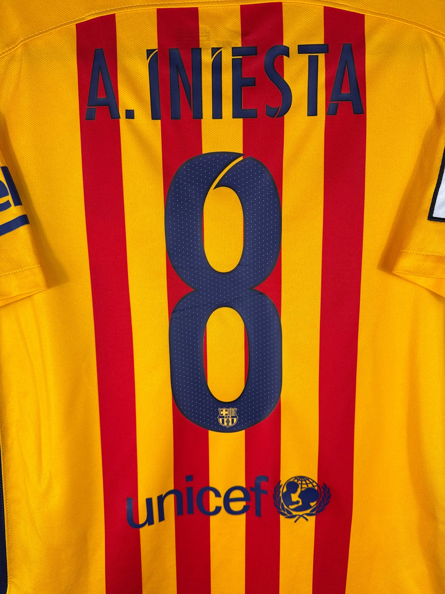 Zoom sur le nom A. INIESTA et le numéro 8 bleu avec typographie officielle du FC Barcelone saison 2015-2016.