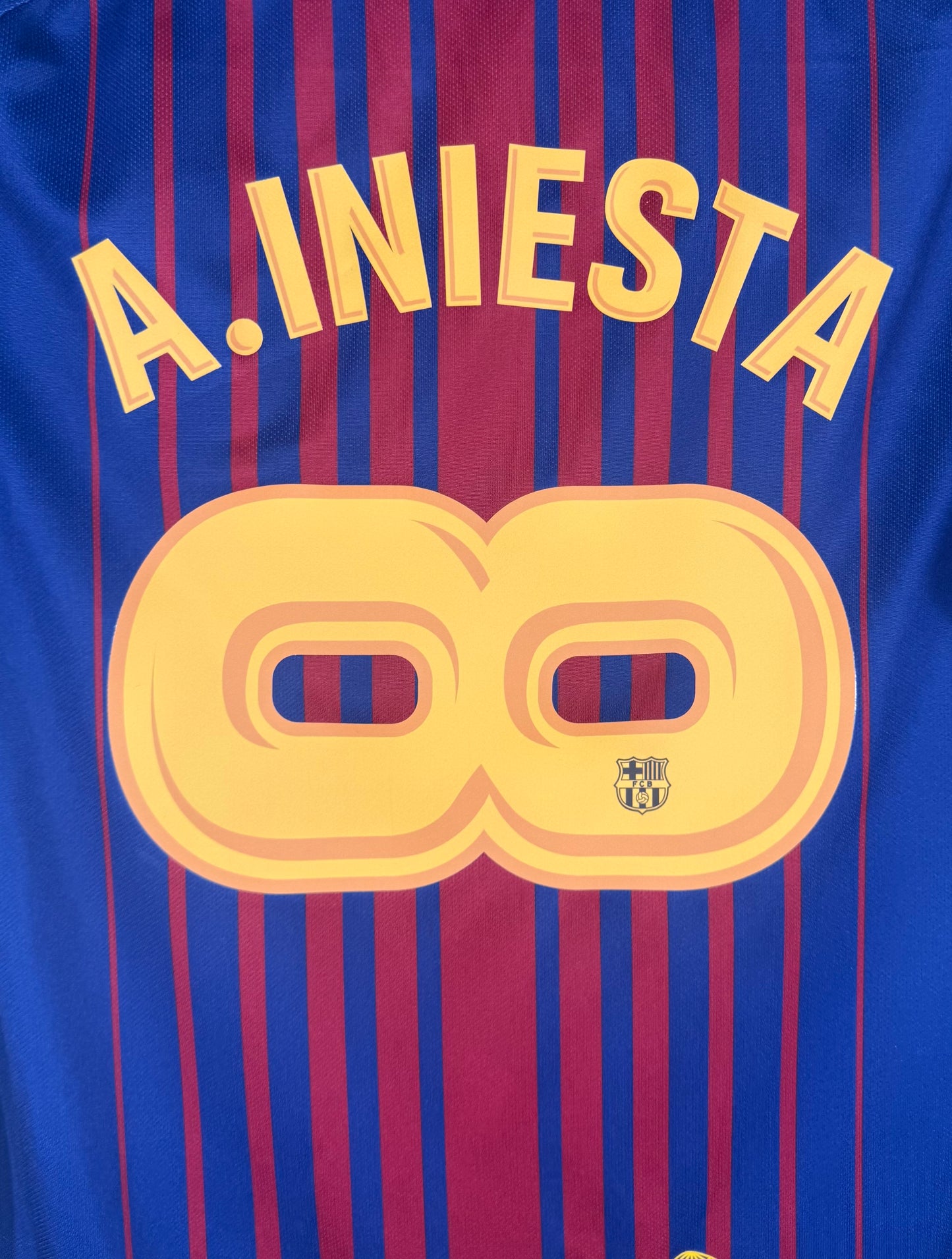 Zoom sur le nom A. INIESTA et le numéro 8 jaune avec le logo Unicef en bas.