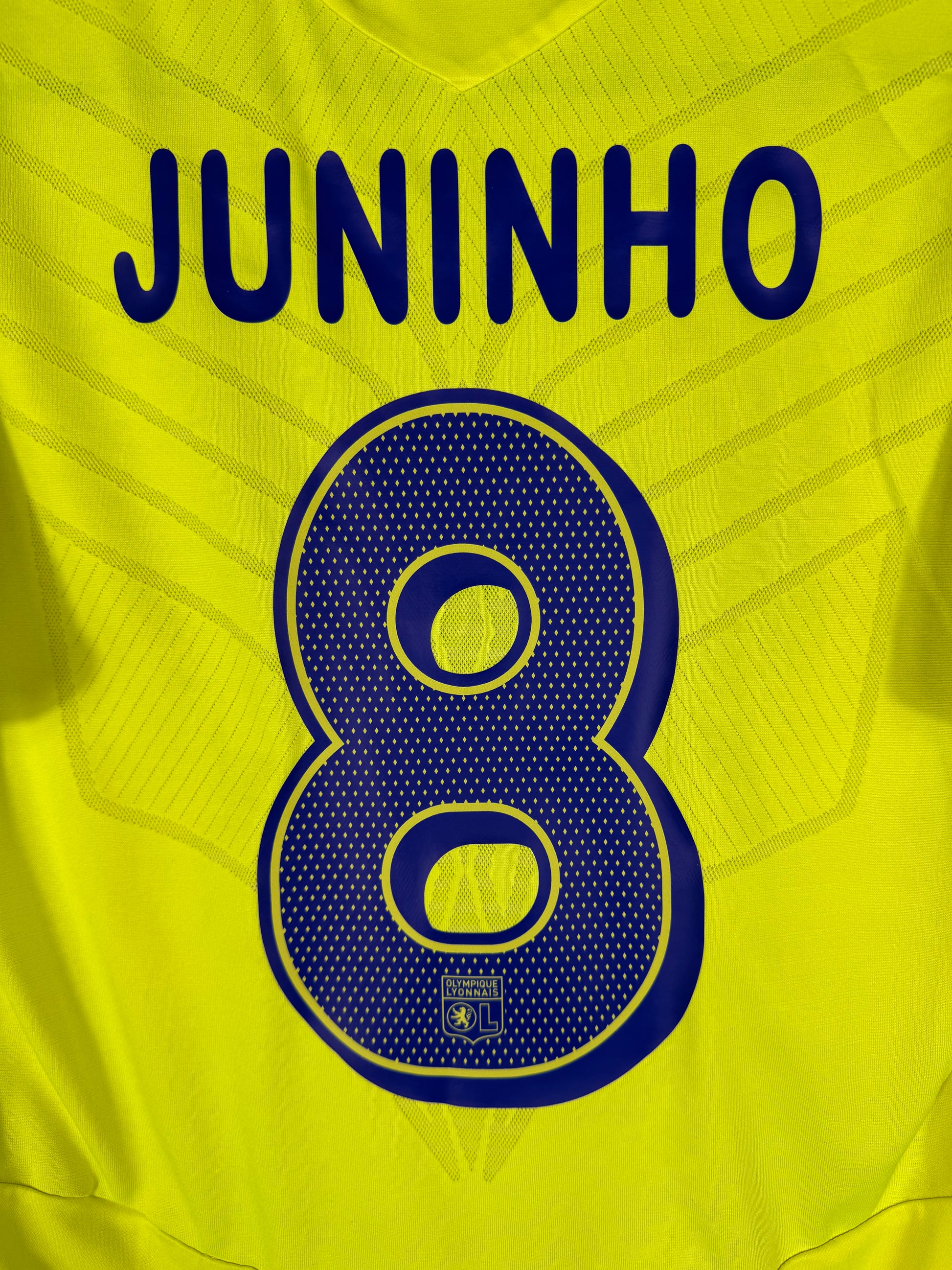 Zoom sur le nom JUNINHO et le numéro 8 bleu marine, typographie officielle utilisée en Ligue des Champions.