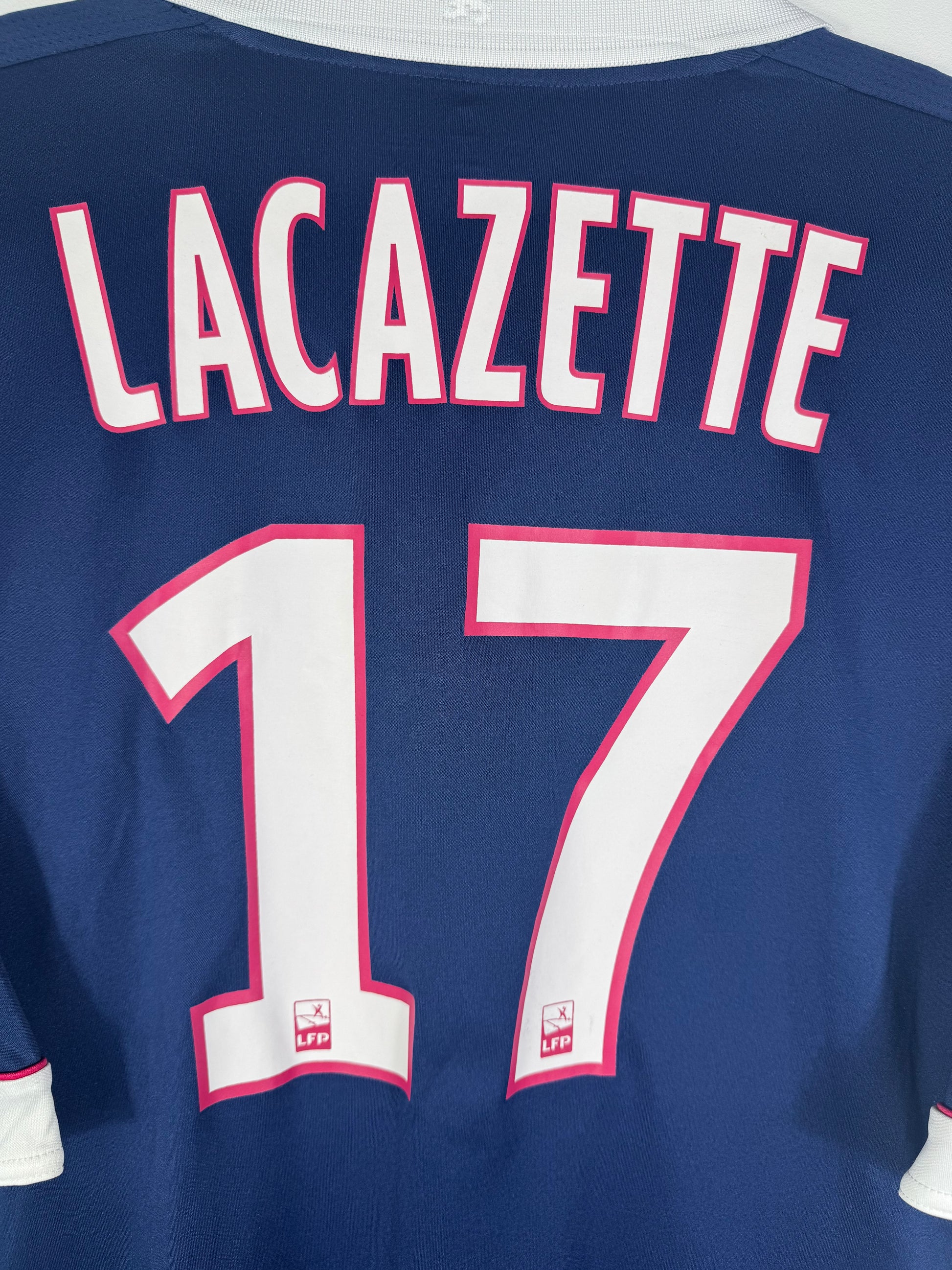 Zoom sur le nom LACAZETTE et le numéro 17 blanc avec liseré rose et blason de l'OL intégré.