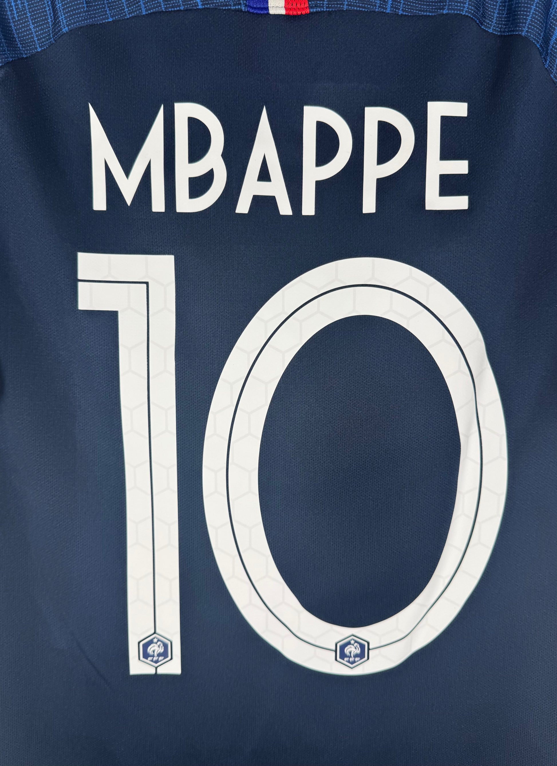 Zoom sur la typographie hexagonale du nom MBAPPE et le numéro 10 blanc.