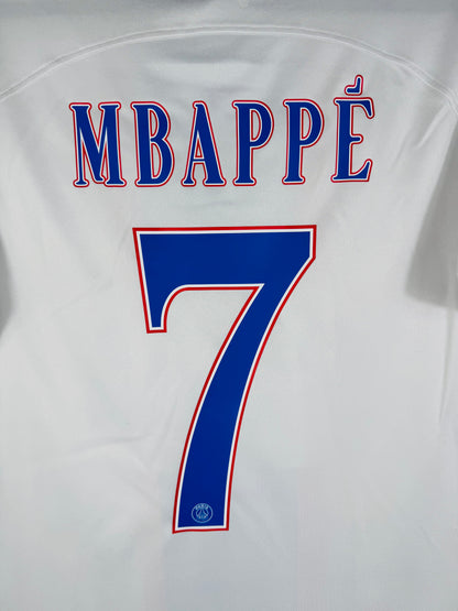 Zoom sur le nom MBAPPÉ et le numéro 7 bleu avec le logo du PSG incrusté au bas du chiffre.