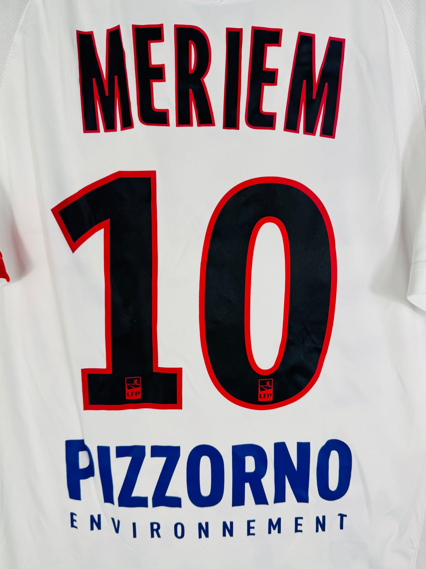 Zoom sur le nom MERIEM, le numéro 10 et le sponsor dorsal Pizzorno Environnement.