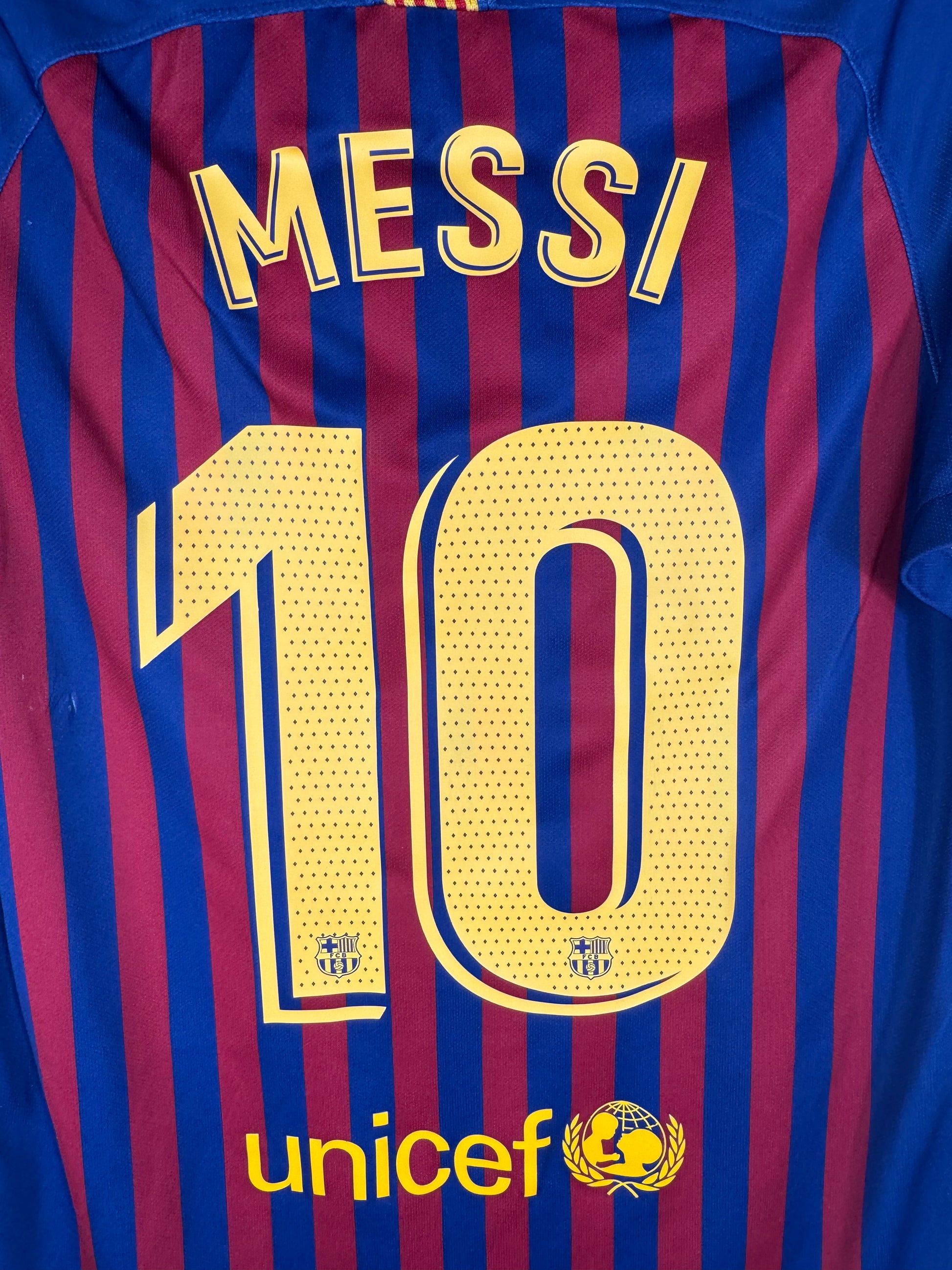 Zoom sur le nom MESSI et le numéro 10 jaune avec logo du Barça intégré au bas du chiffre.