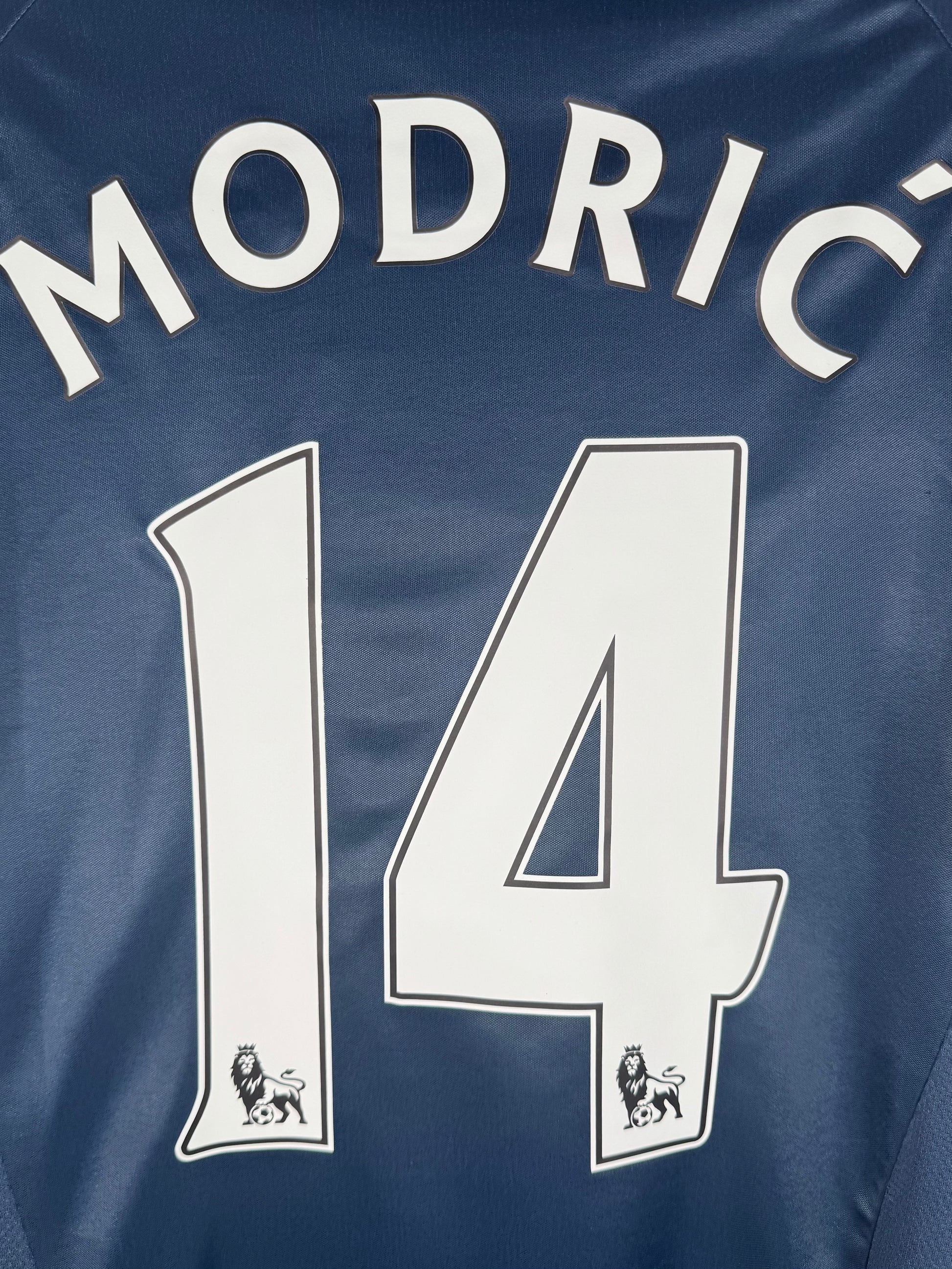 Zoom sur le nom MODRIC et le numéro 14 en typographie officielle Premier League blanche.