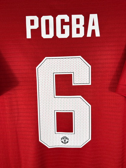 Zoom sur le nom POGBA et le numéro 6 blanc, typographie officielle Manchester United pour les Coupes avec le blason intégré.