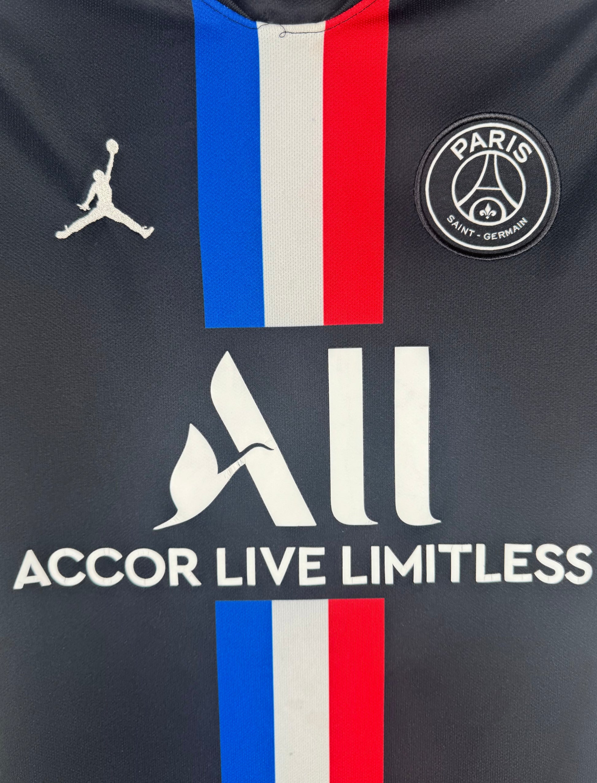Gros plan sur le logo Jordan, l'écusson PSG et le sponsor ALL sur la bande bleu-blanc-rouge.