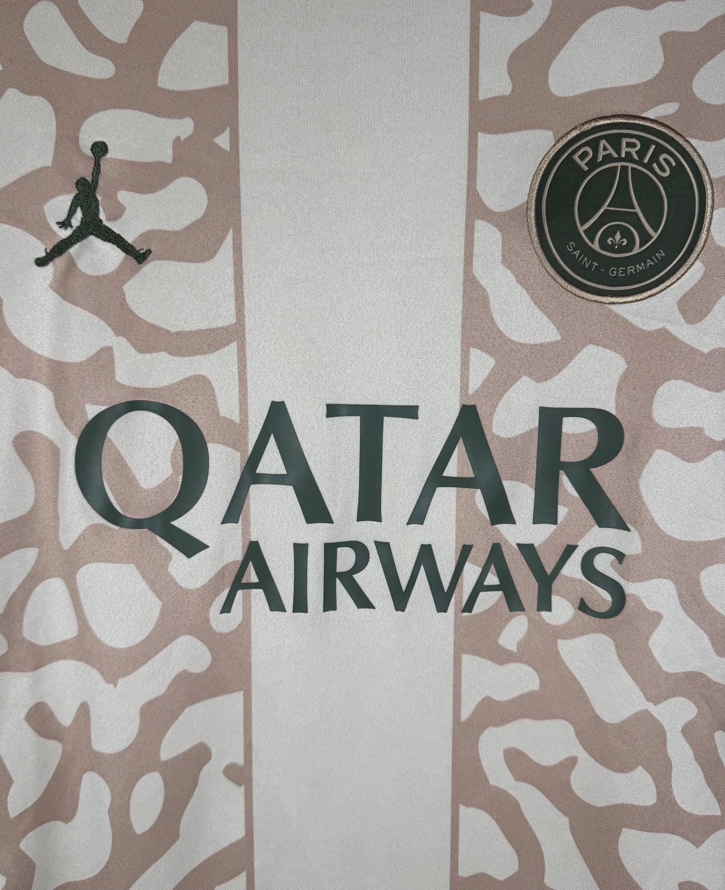 Gros plan sur le logo Jordan noir, l'écusson PSG et le motif craquelé Elephant Print.