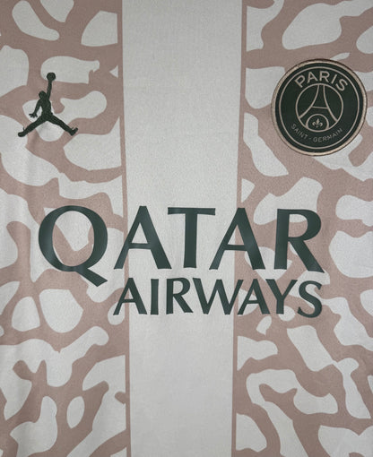 Gros plan sur le logo Jordan noir, l'écusson PSG et le motif craquelé Elephant Print.