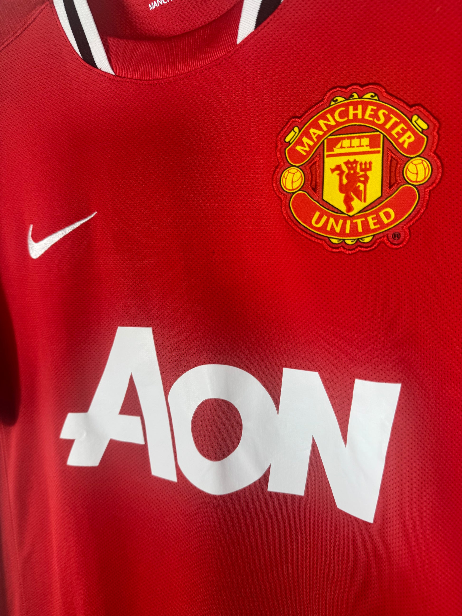 Gros plan sur l'écusson brodé de Manchester United et le sponsor AON sur maillot 2012.